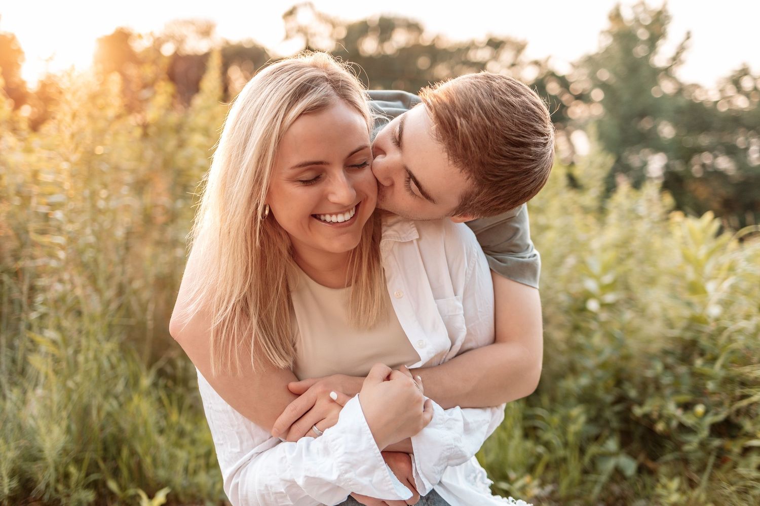 Couple laughing together during golden hour photography session in nature.