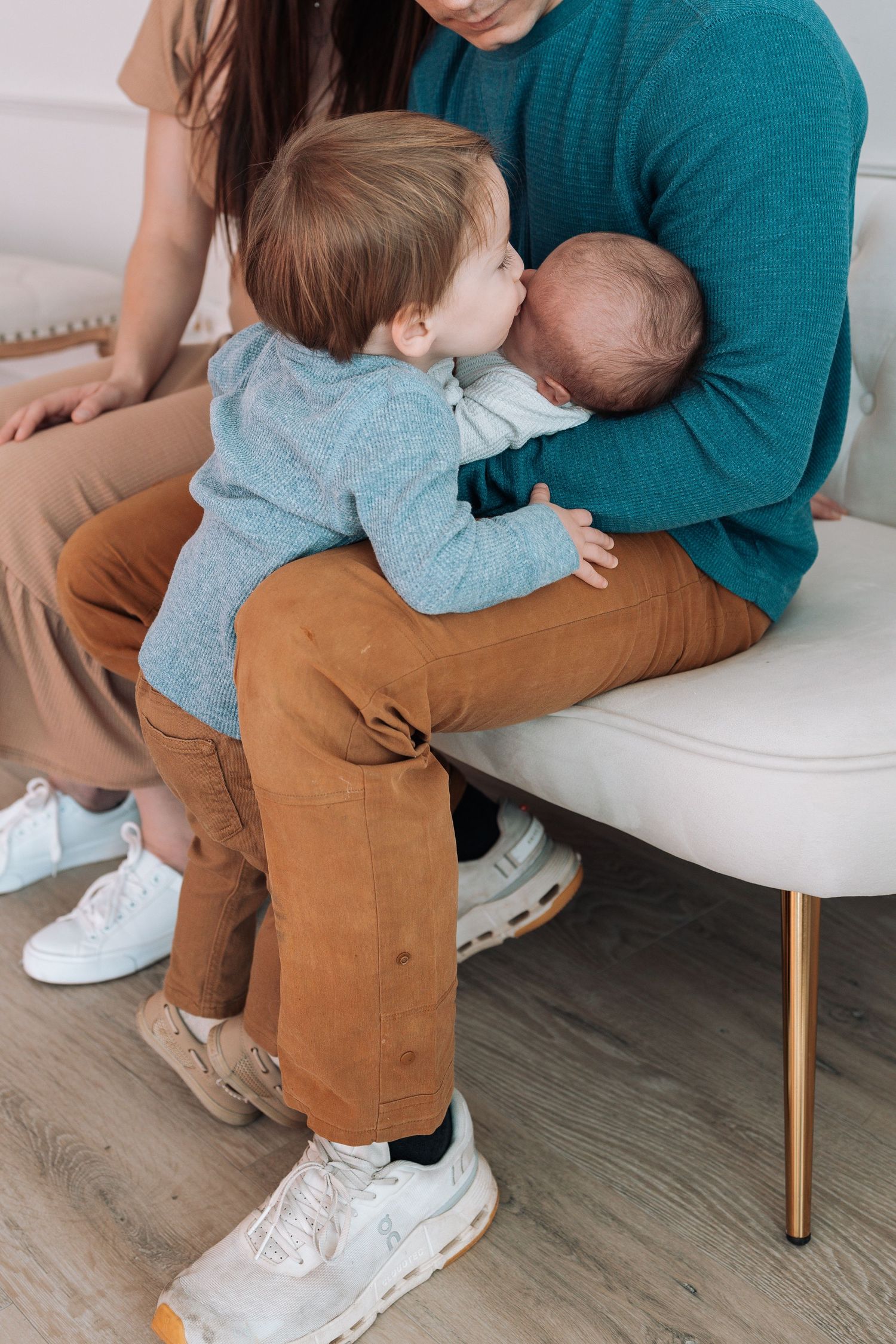 Intimate family moment captured on white chair showing gentle embraces.