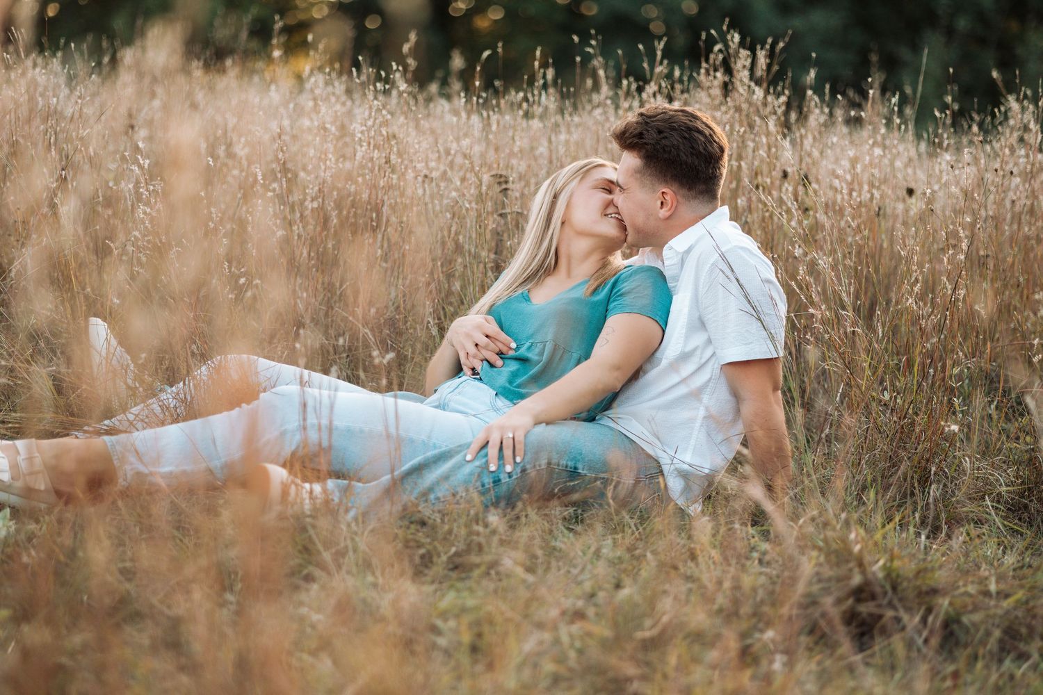 Couple relaxing together in golden field at sunset.