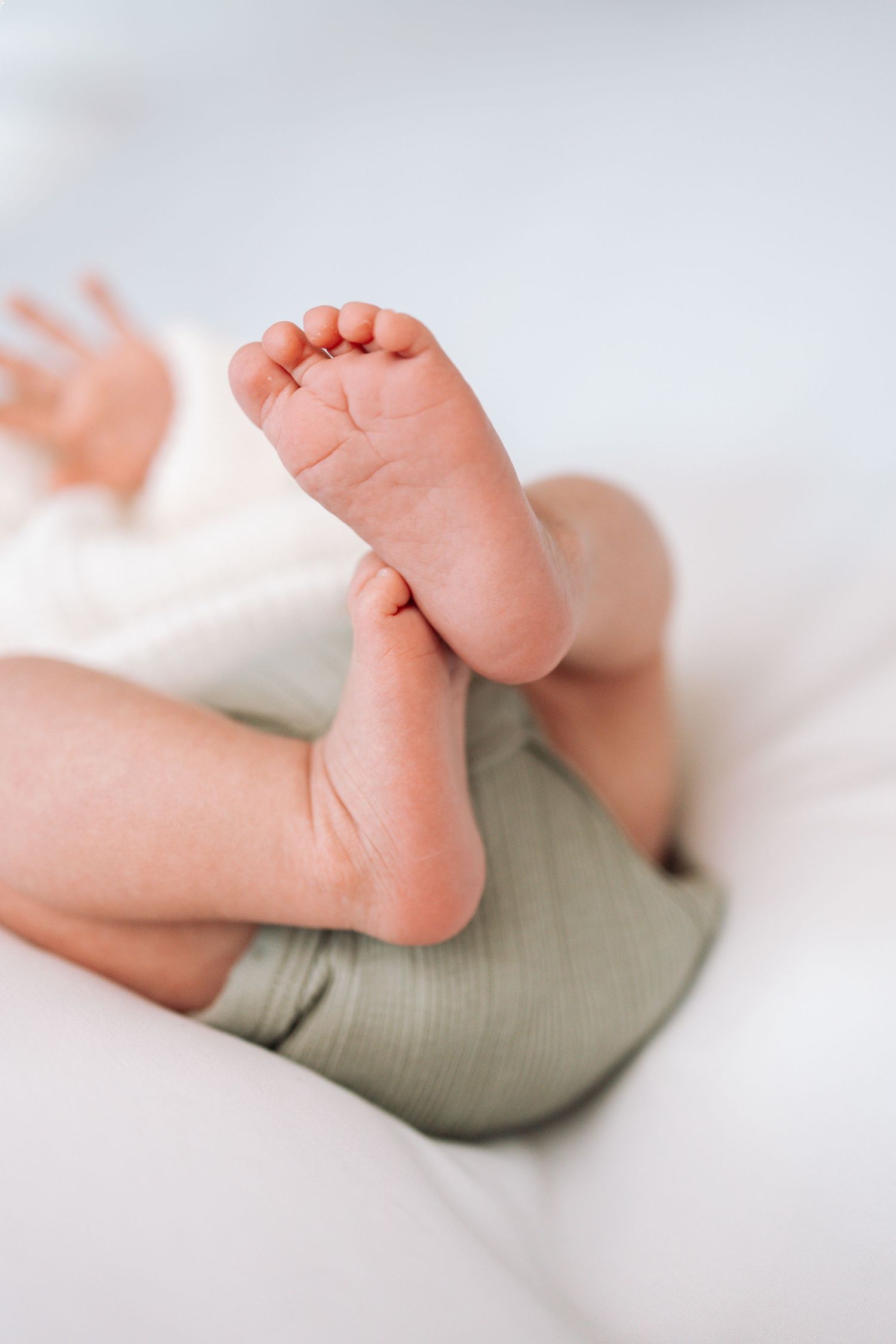 Close-up of tiny baby feet against soft white background showing delicate details.