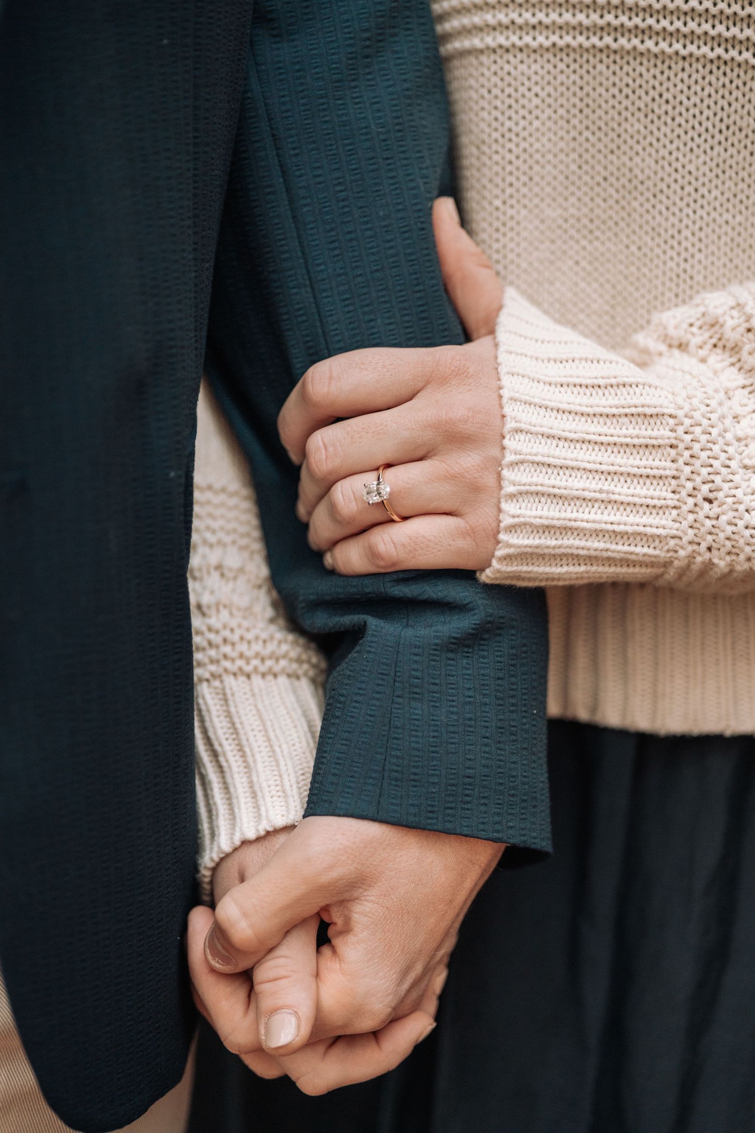 Close-up of hands holding each other, showing knit sweater details.