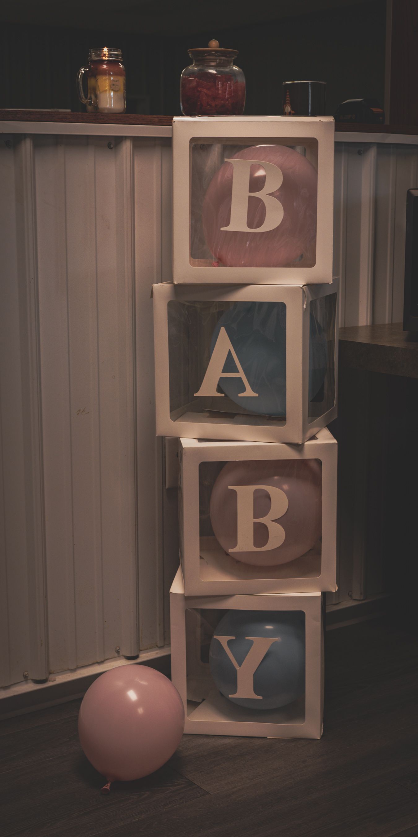 Stacked BABY letter boxes with pink and blue balloons for a gender reveal party decoration.