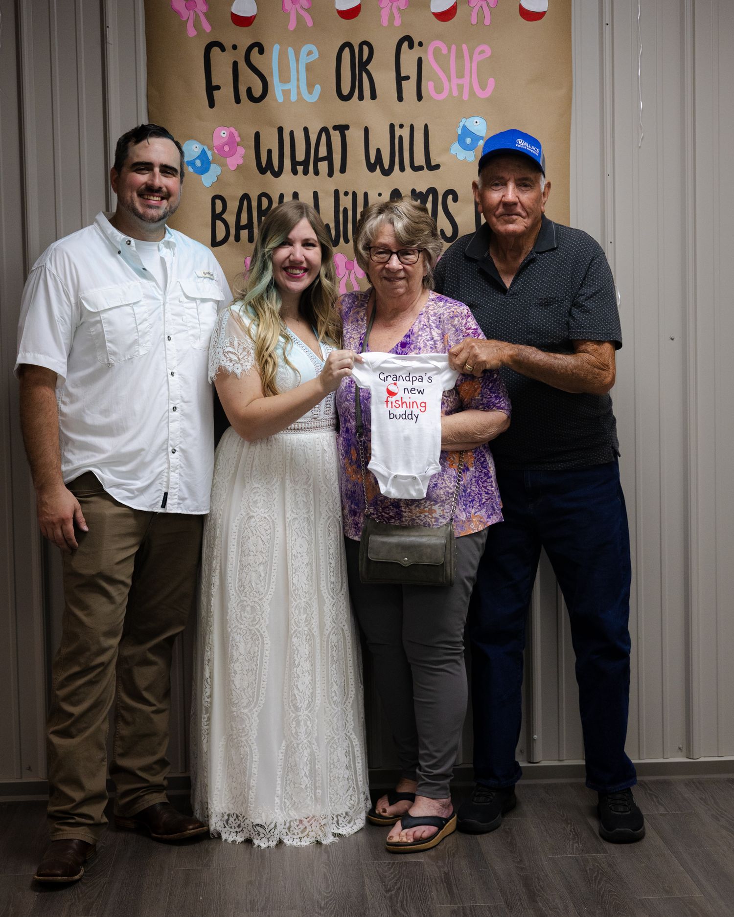 Two couples posing at a FisHe or FiShe gender reveal party holding a baby onesie.