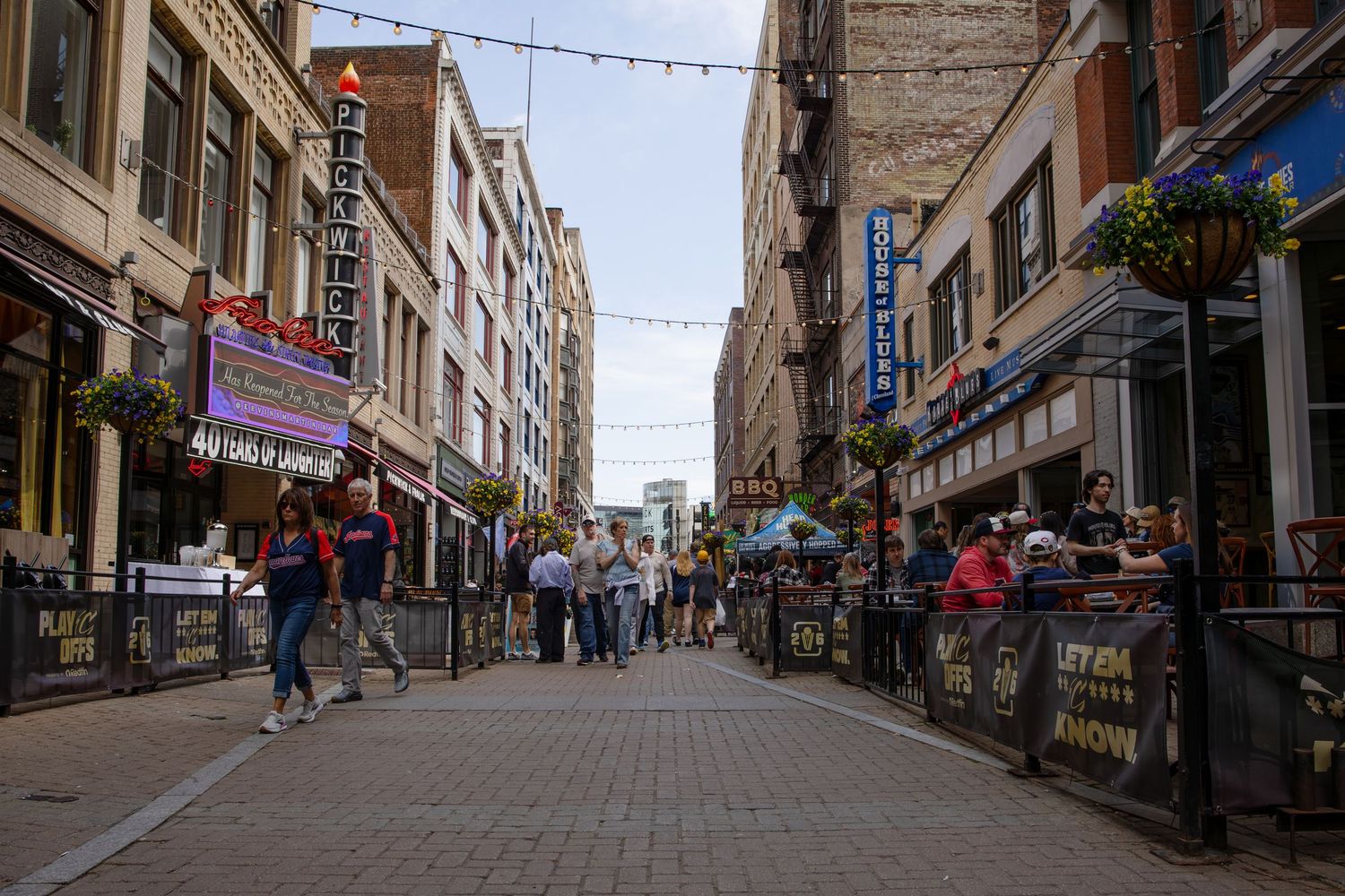 Busy pedestrian street lined with bars and restaurants in a vibrant urban entertainment district on a sunny day.