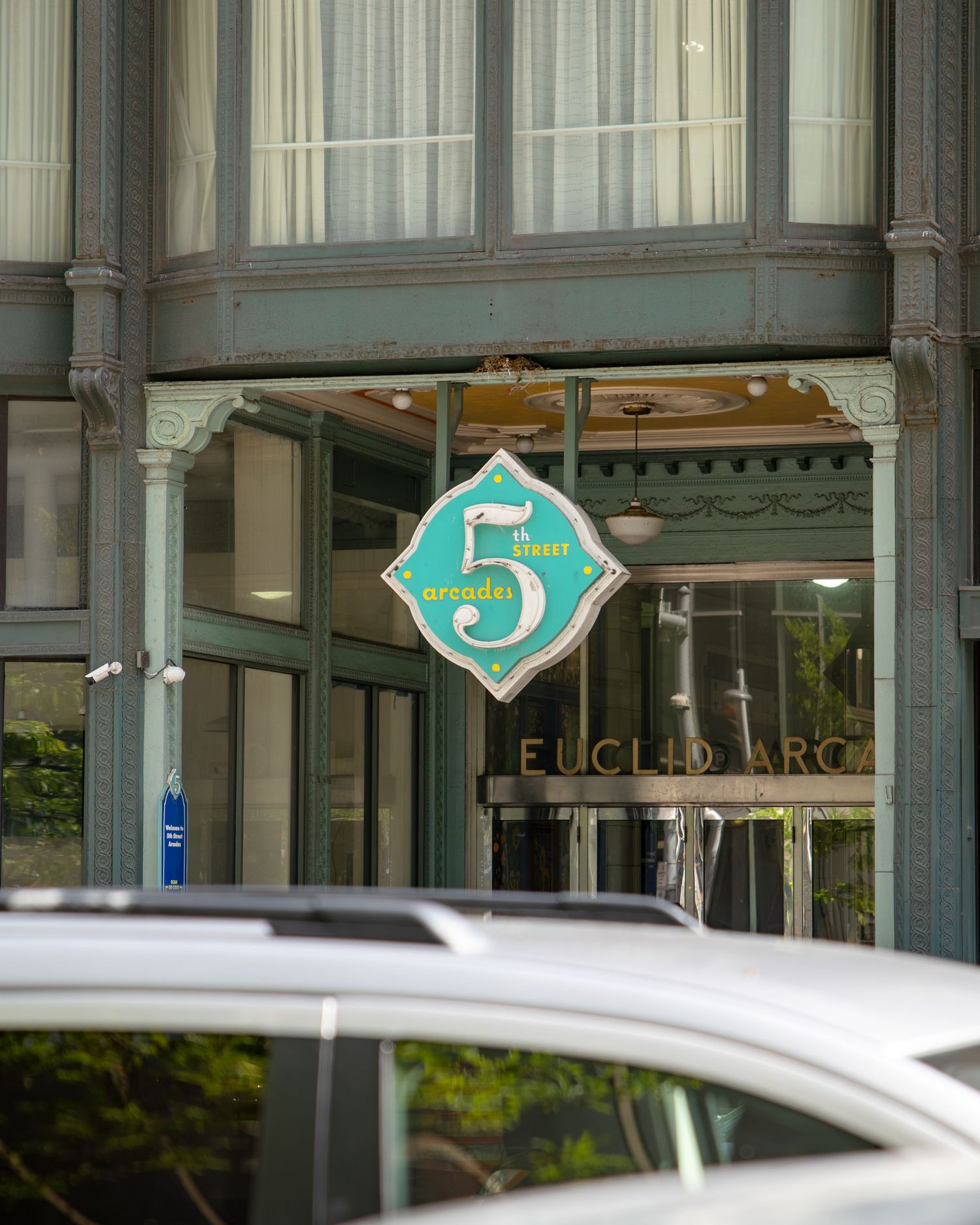 Euclid Arcade entrance featuring a teal diamond-shaped sign with the number 5, on a historic building facade.