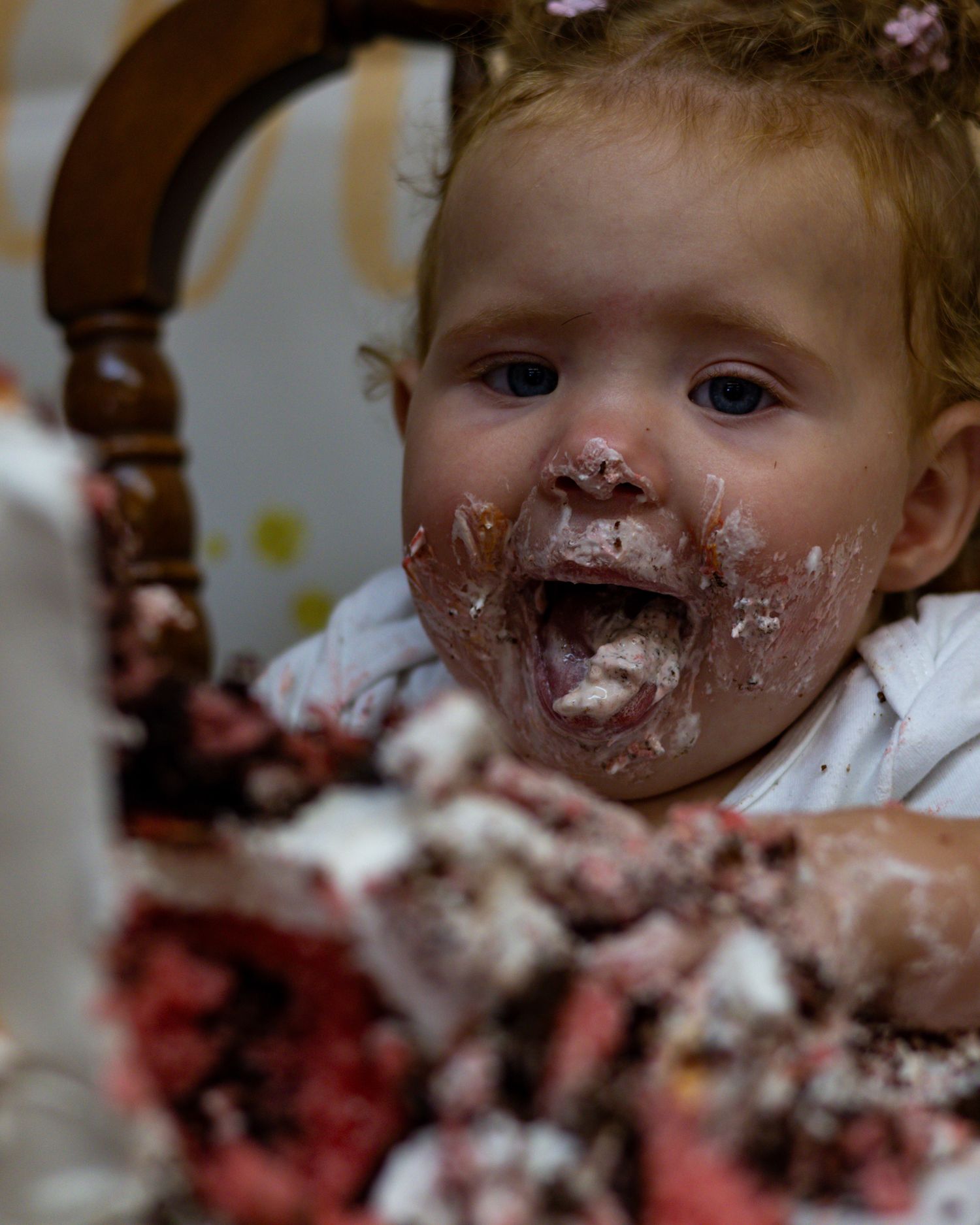 Adorable baby with chocolate cake smeared on face during first birthday cake smash celebration.