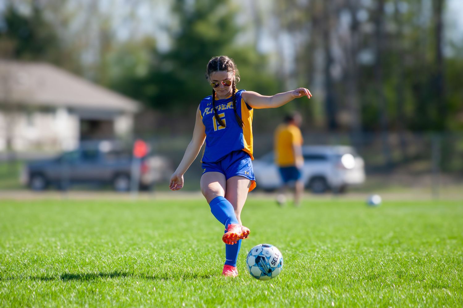 Soccer player in blue uniform prepares to kick ball on grass field.
