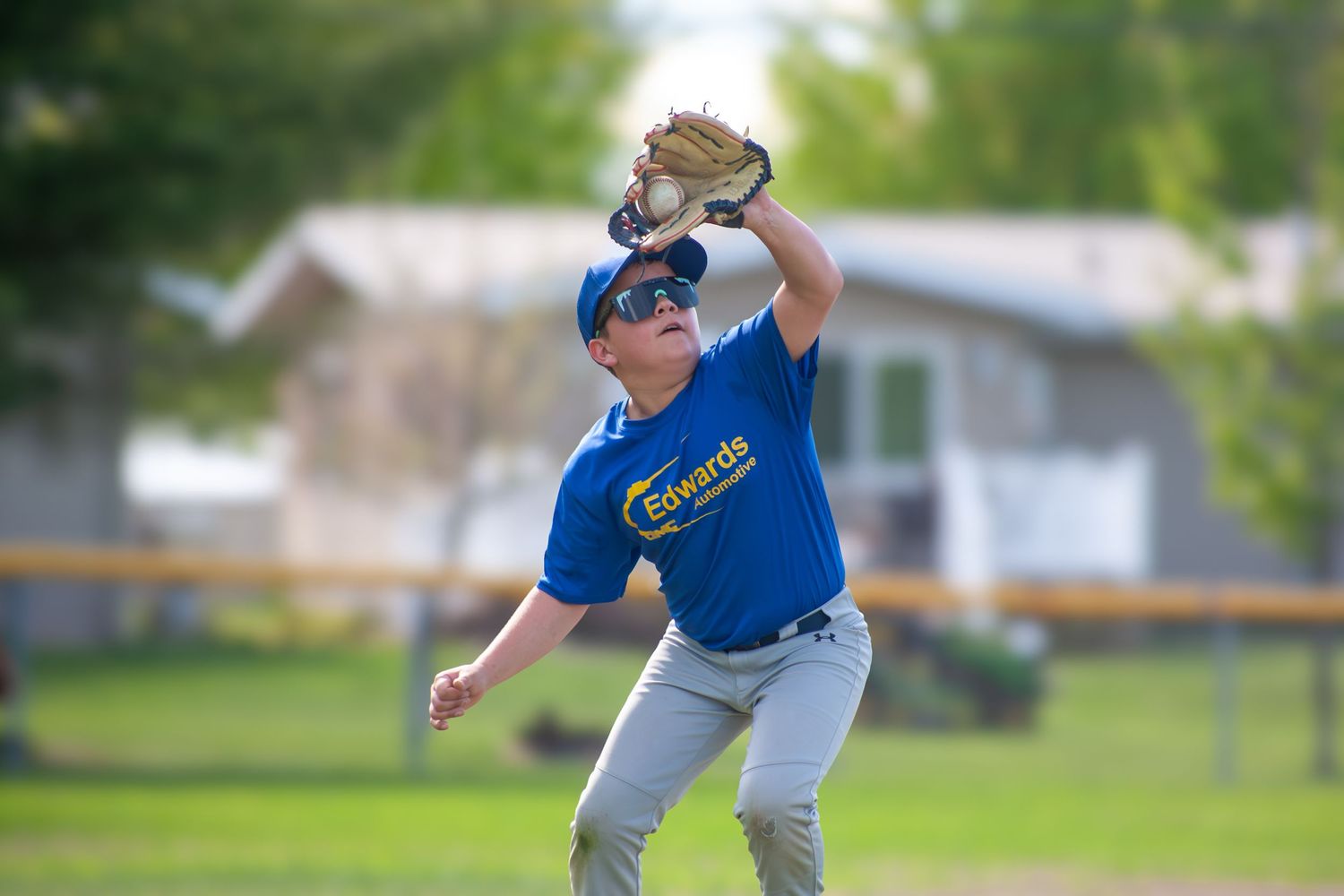 Baseball player in blue uniform catches ball during game practice.