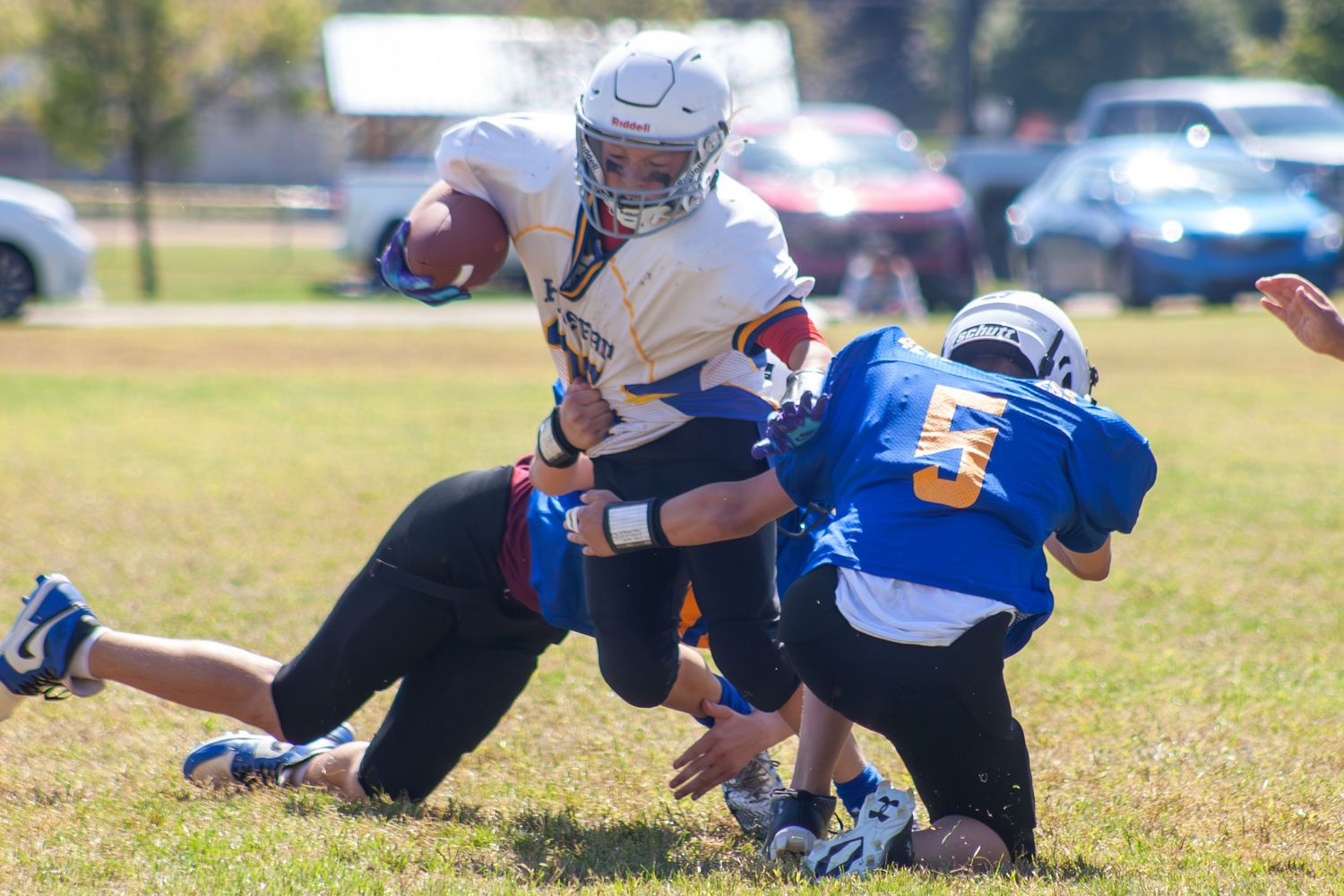 Youth football players collide during a tackle play on the grass field.
