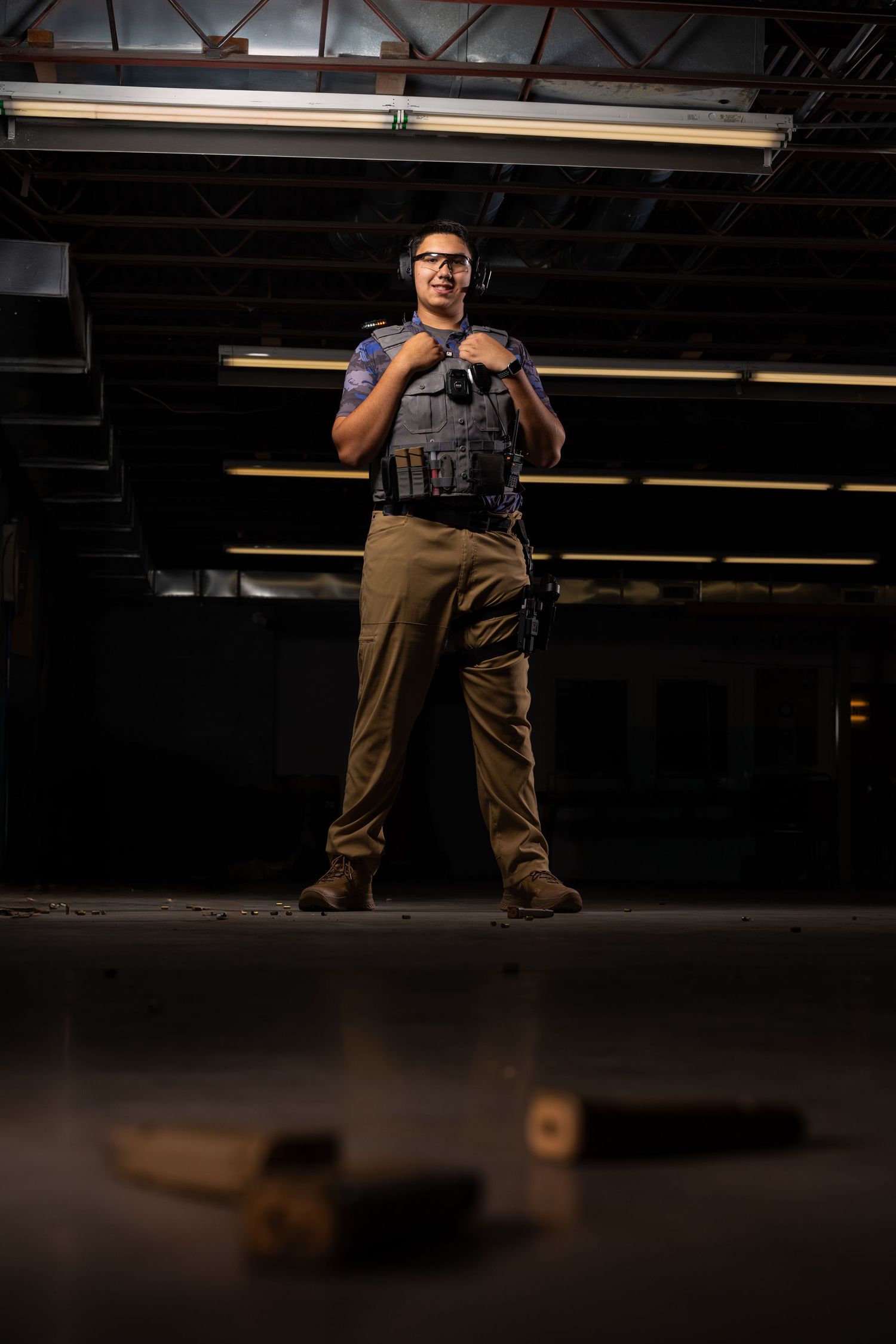 Person in tactical gear poses dramatically in dark indoor setting.
