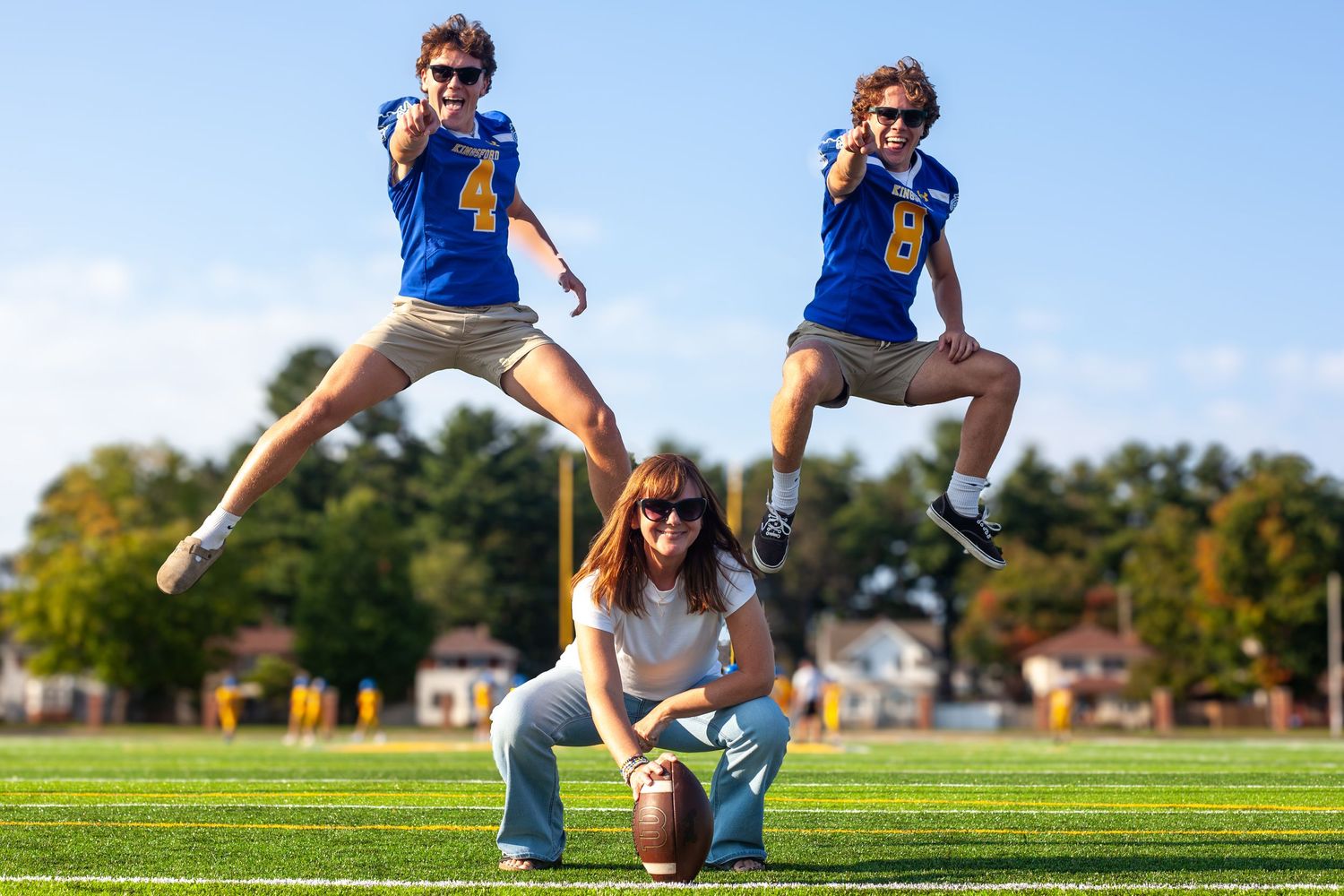 Series of dynamic jumping poses captured against blue sky on grassy field.