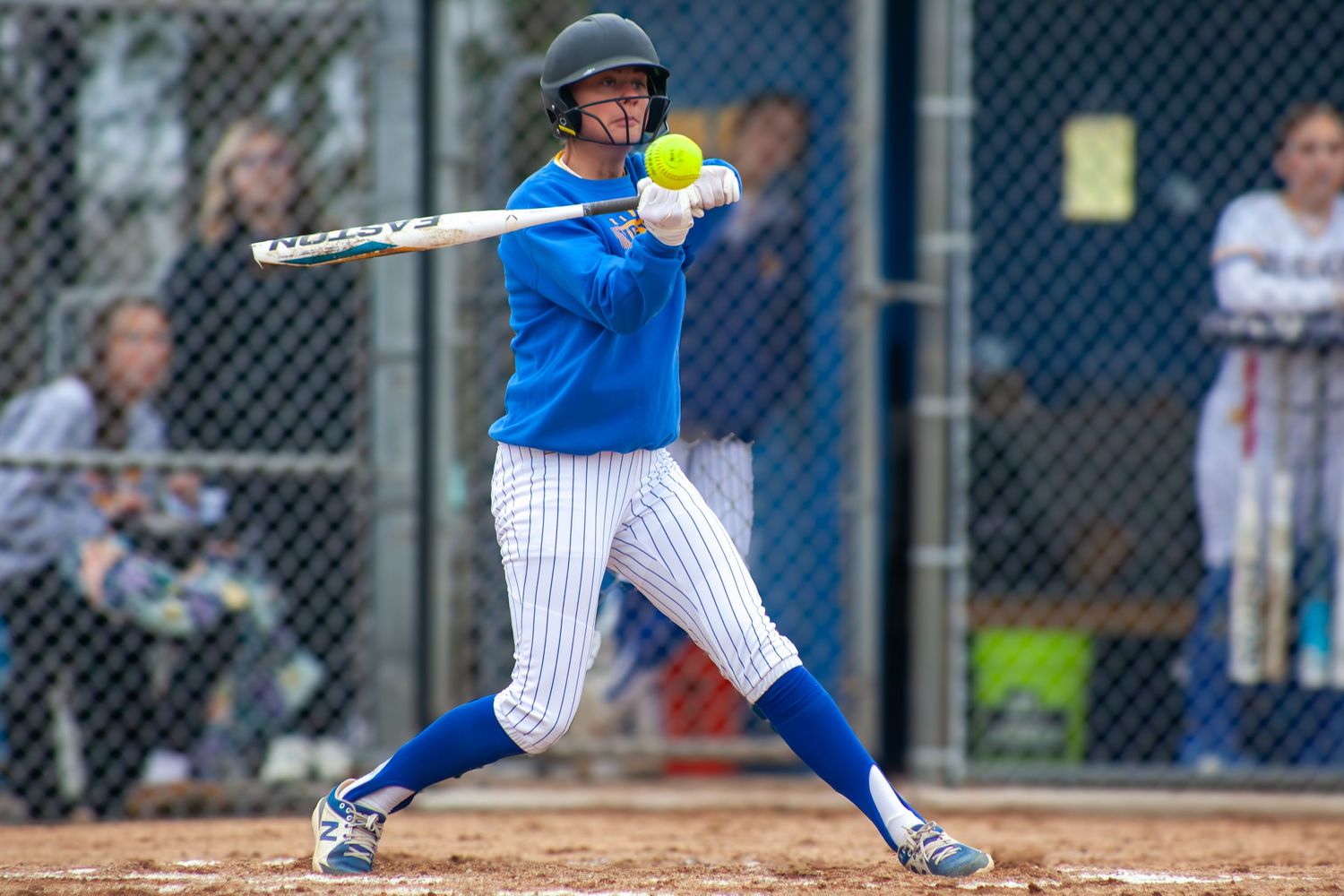 Baseball batter in blue striped uniform swings at pitch during game.