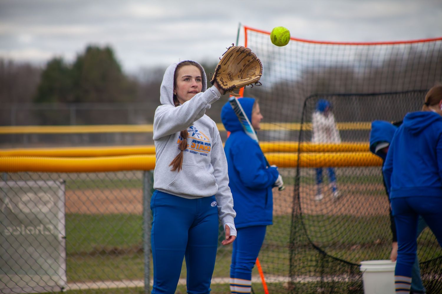 Softball player practices catching with glove during team training.