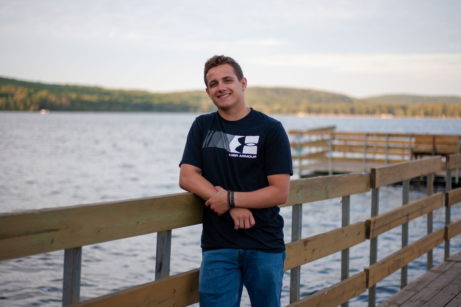 People posing along wooden dock overlooking scenic lake at sunset.