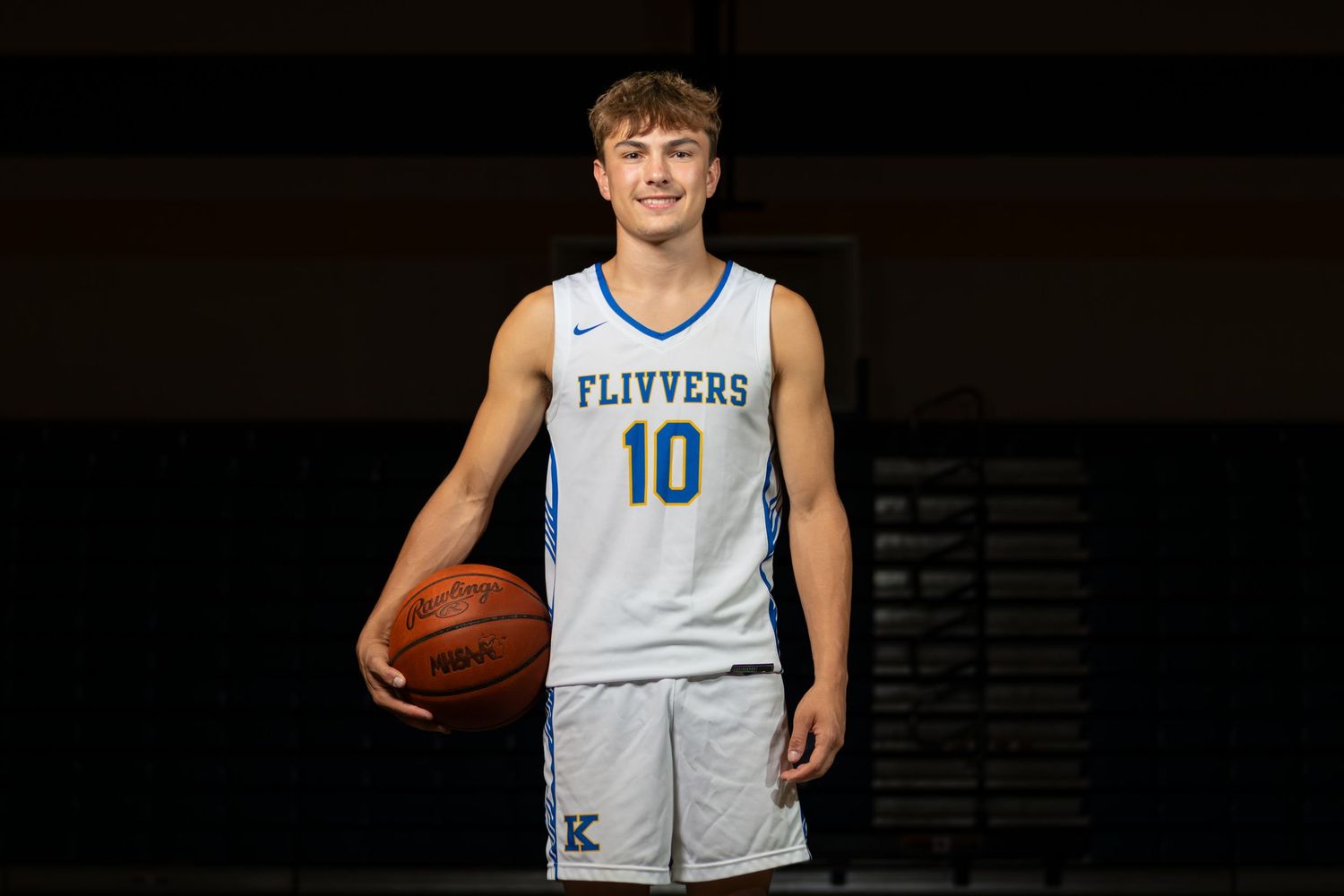 High school basketball player #10 in Flivvers jersey poses with ball for team photo.