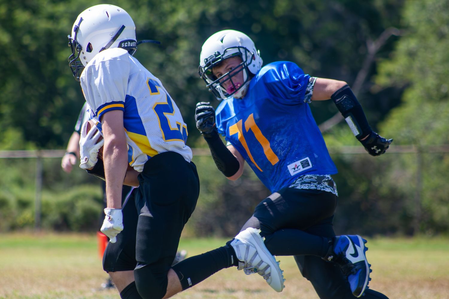 Two football players in blue and white uniforms compete during a game.