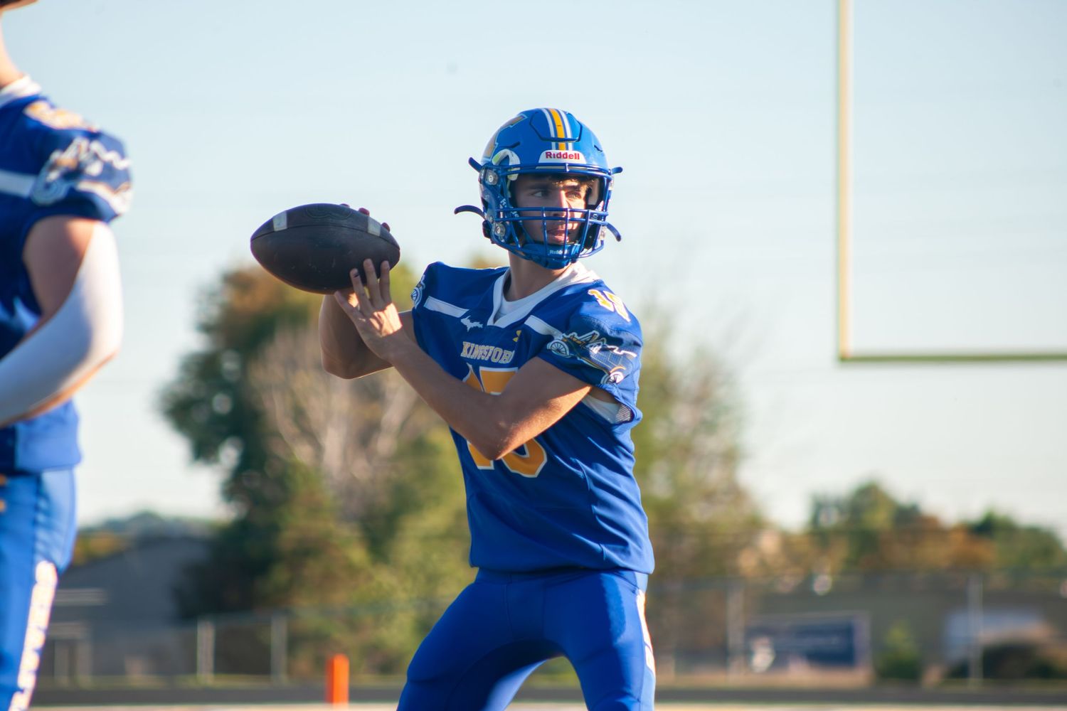 Football player in blue uniform prepares to throw the ball during game.