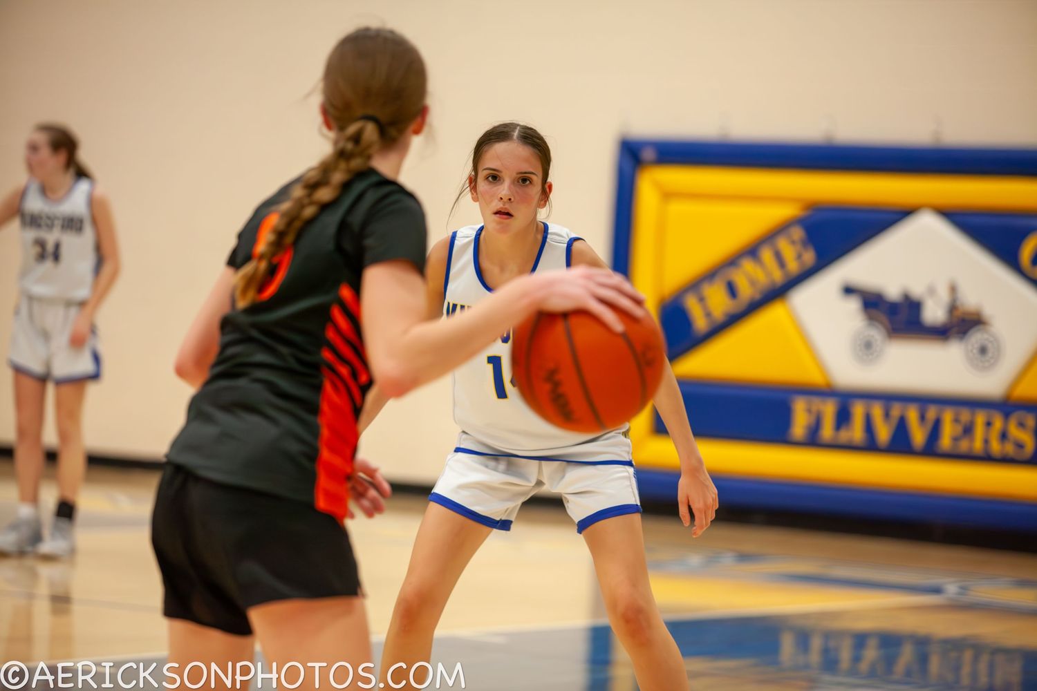 Basketball players compete during an intense game with a blue and yellow banner visible in the background.