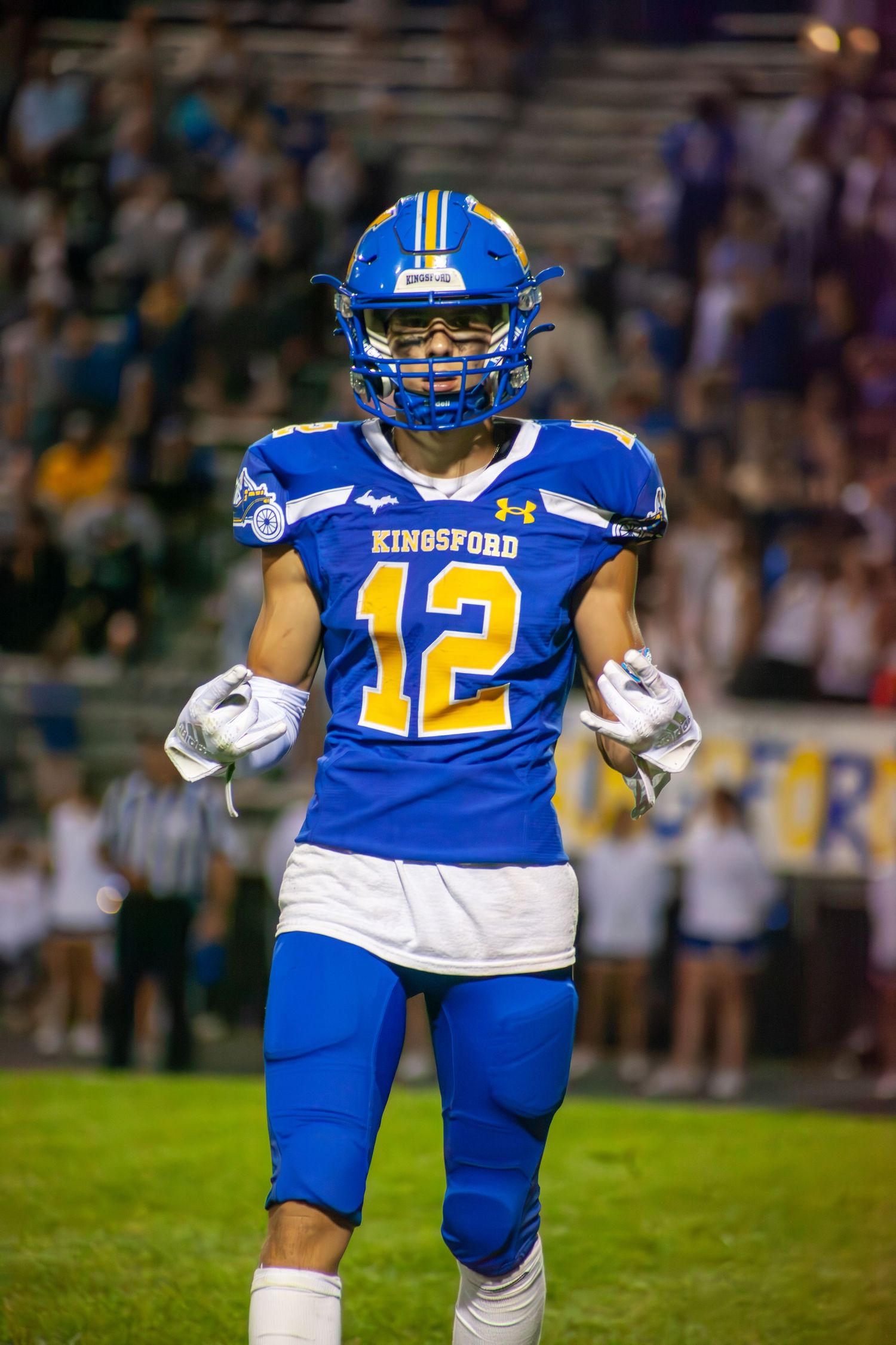 Football player in blue and gold Kingsford uniform stands ready on the field.