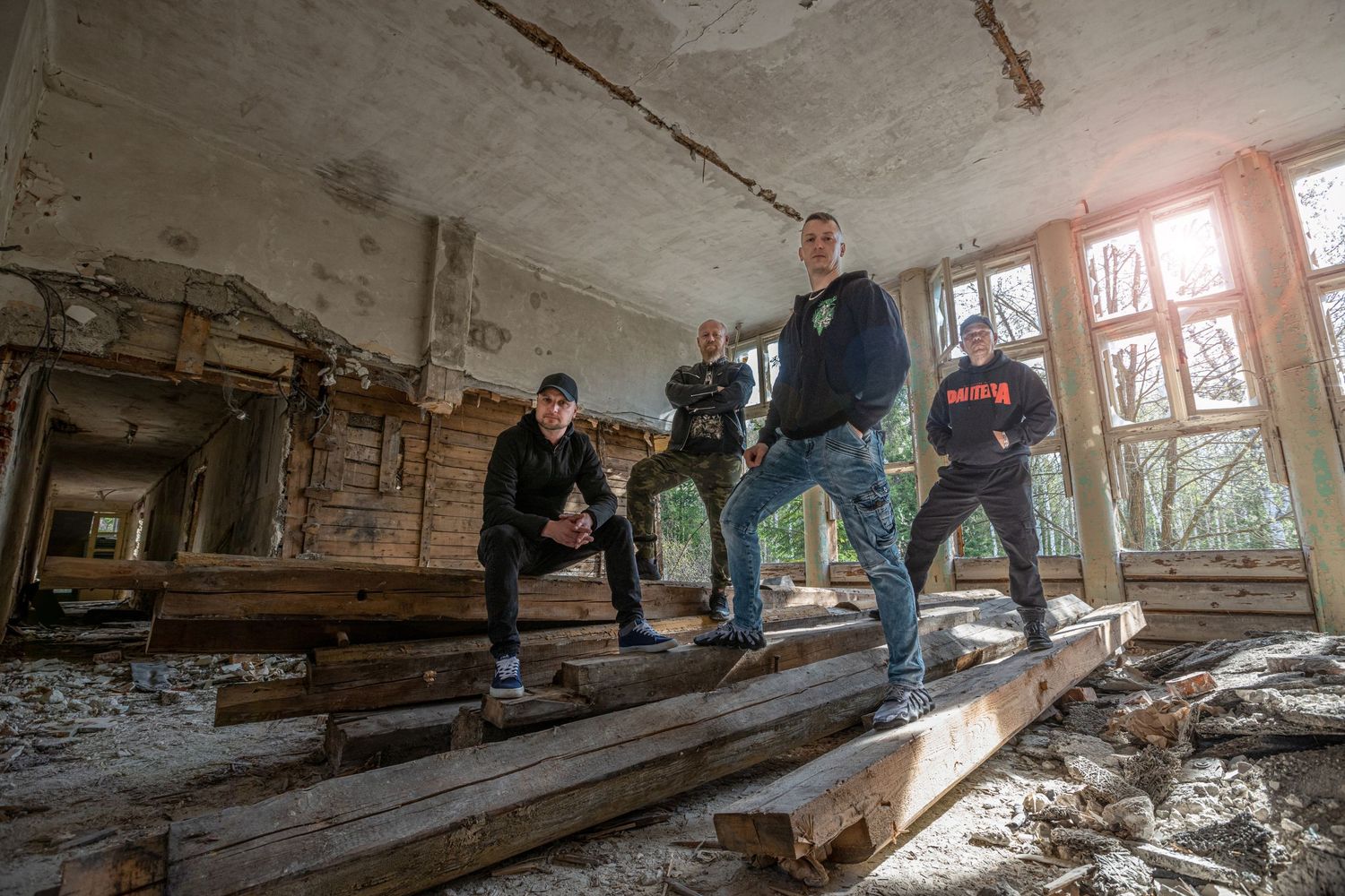 Explorers walk through debris-filled hallway of an abandoned structure.