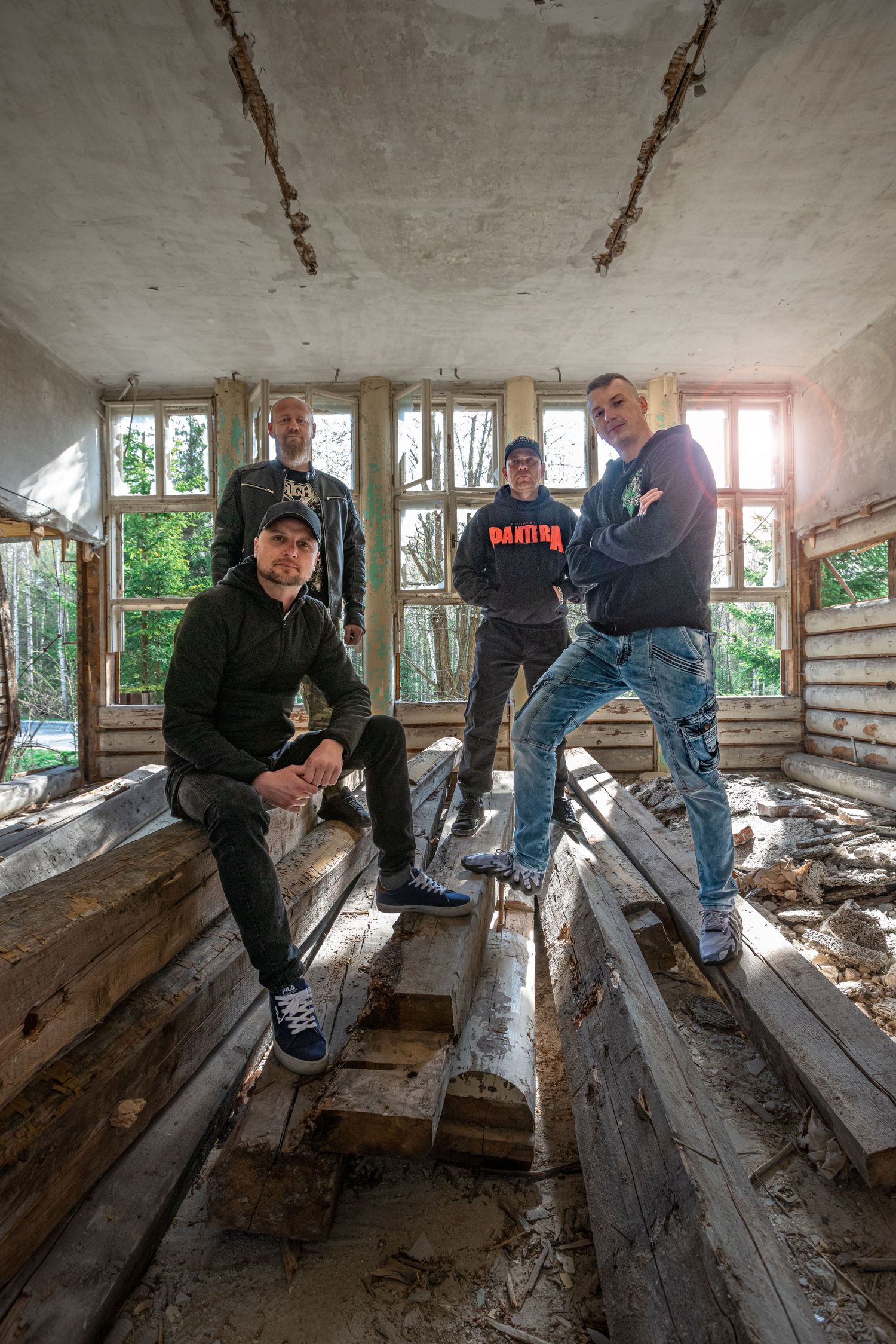 Urban explorers examine damaged wooden floorboards in an abandoned room.