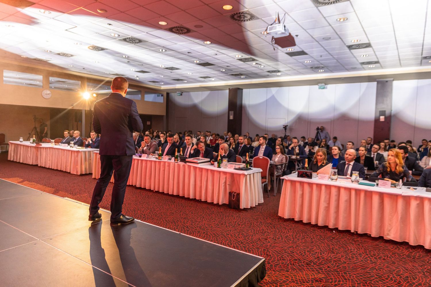 Wide view of conference room setup with tables and projection screens.