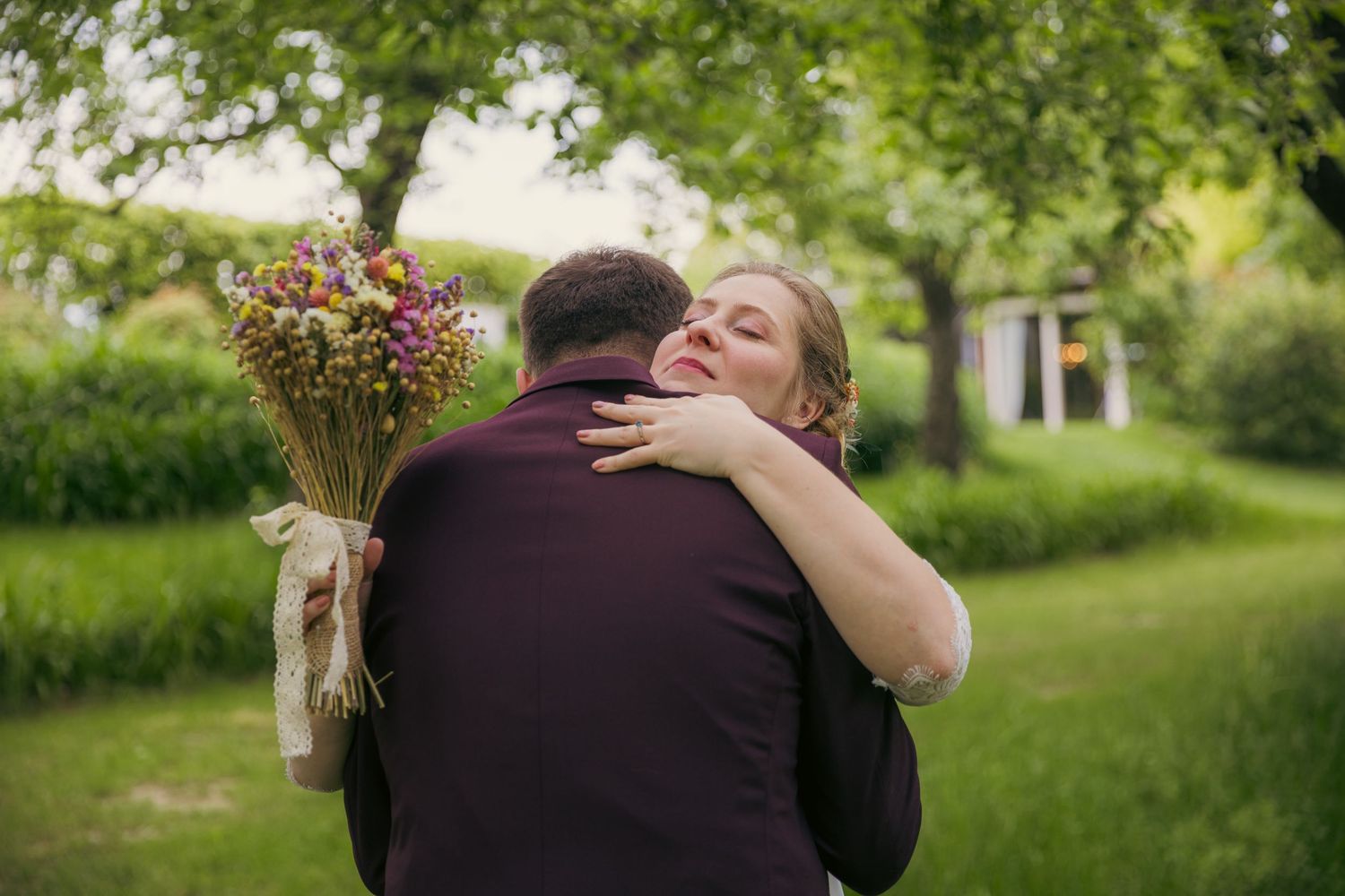 Tender embrace between newlyweds in a lush garden setting.