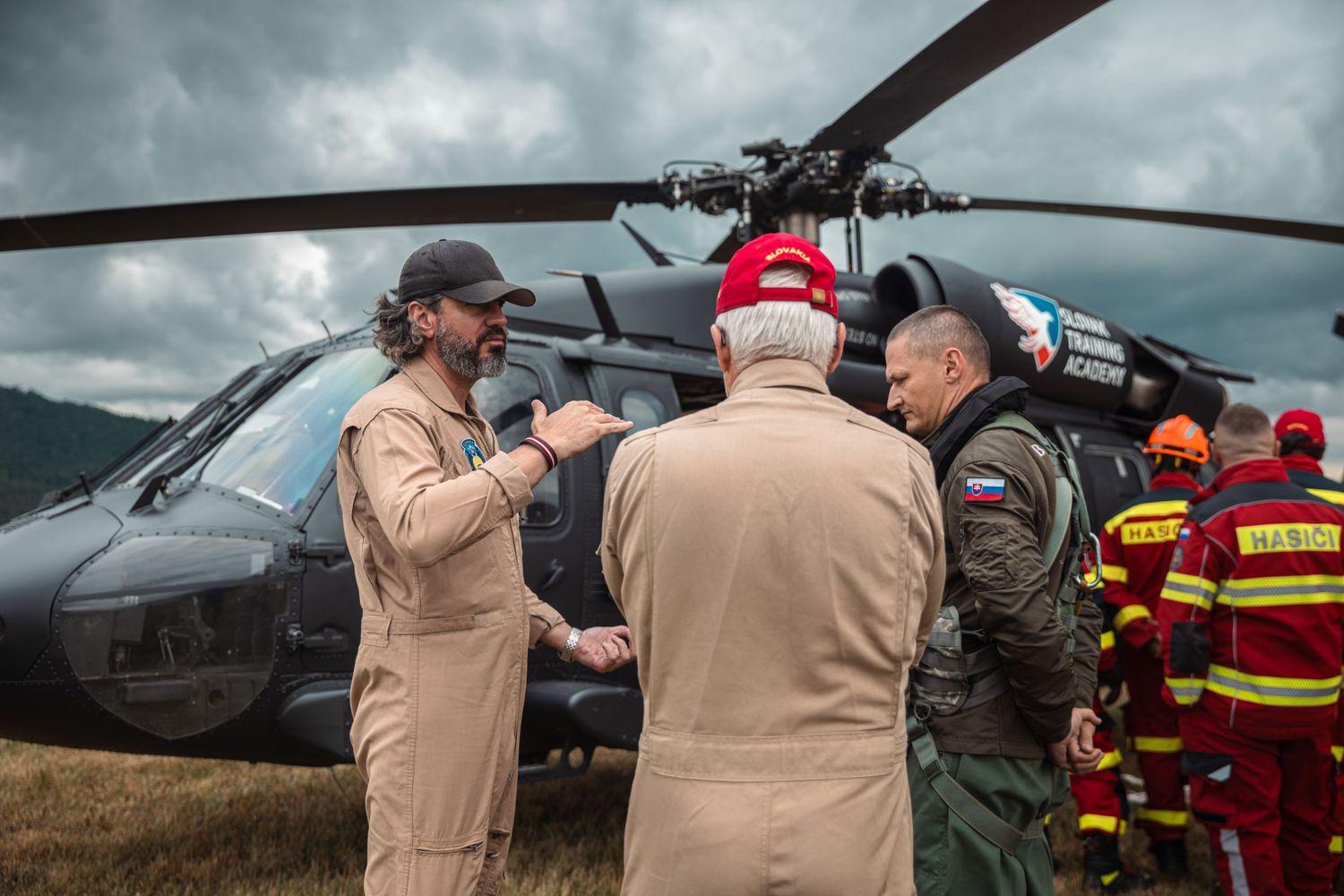 Military personnel and firefighters gather near helicopter during joint emergency response training.