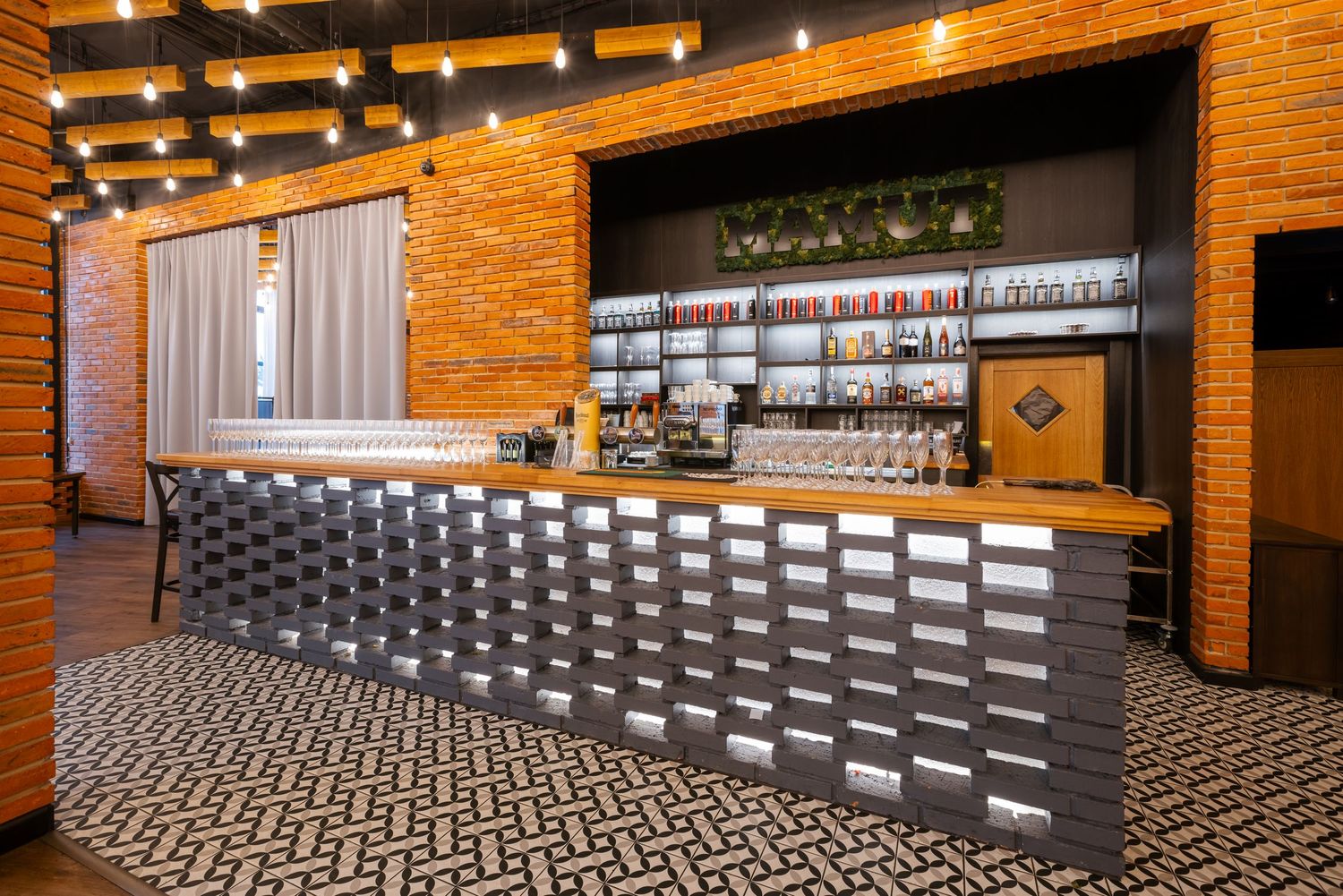 Modern restaurant space with exposed brick walls and geometric tile flooring patterns.