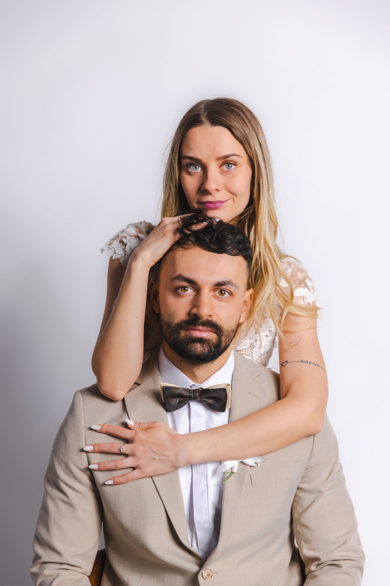 Playful wedding portrait series with couple in beige suit and white lace dress.