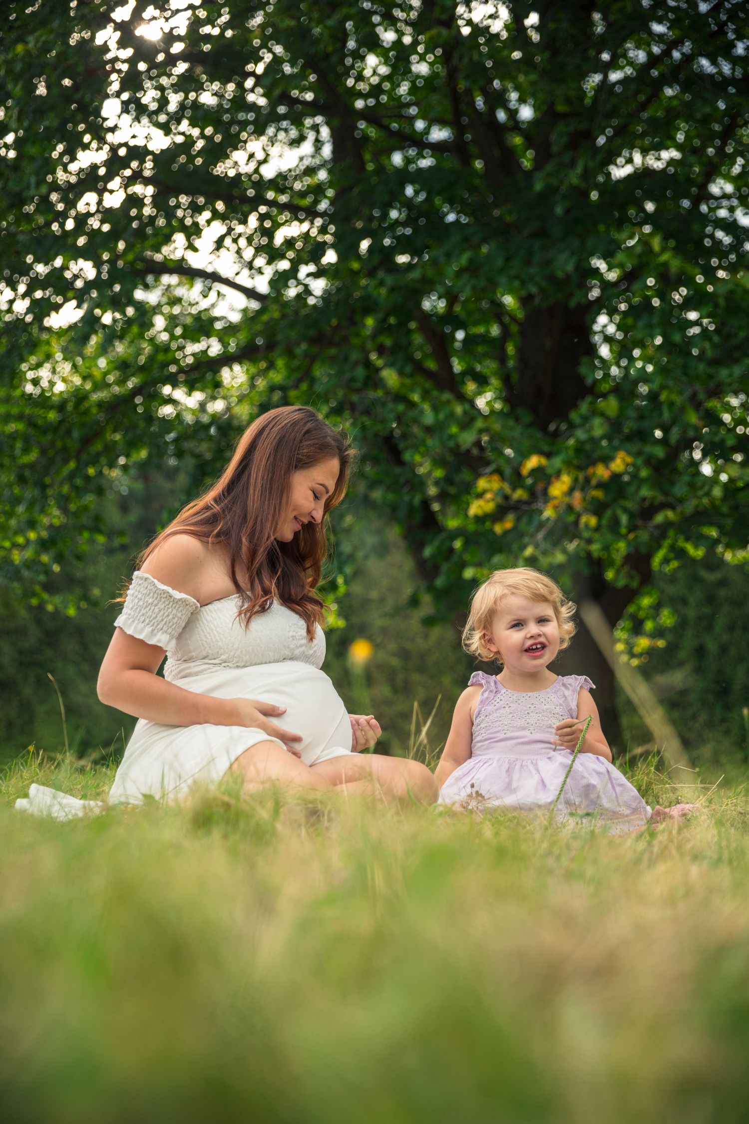 Mother and child share a happy moment while sitting in summer meadow.