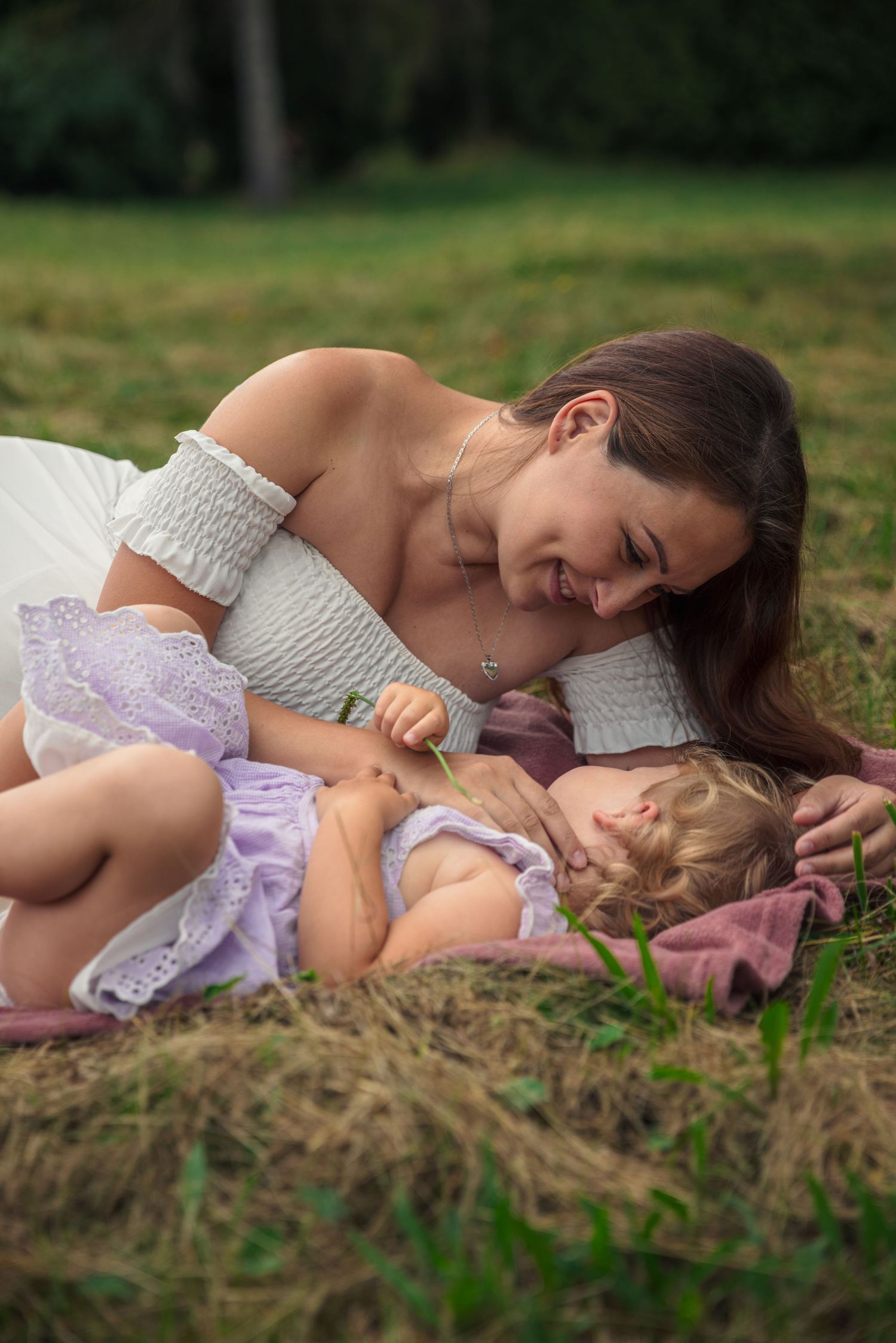 Sweet candid moment between mother and child laying in grass.