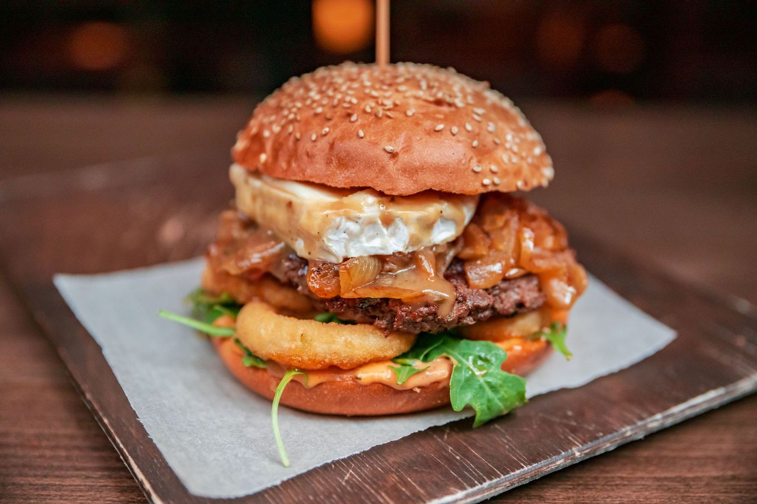 Artisanal hamburgers arranged on wooden serving boards with fresh ingredients.