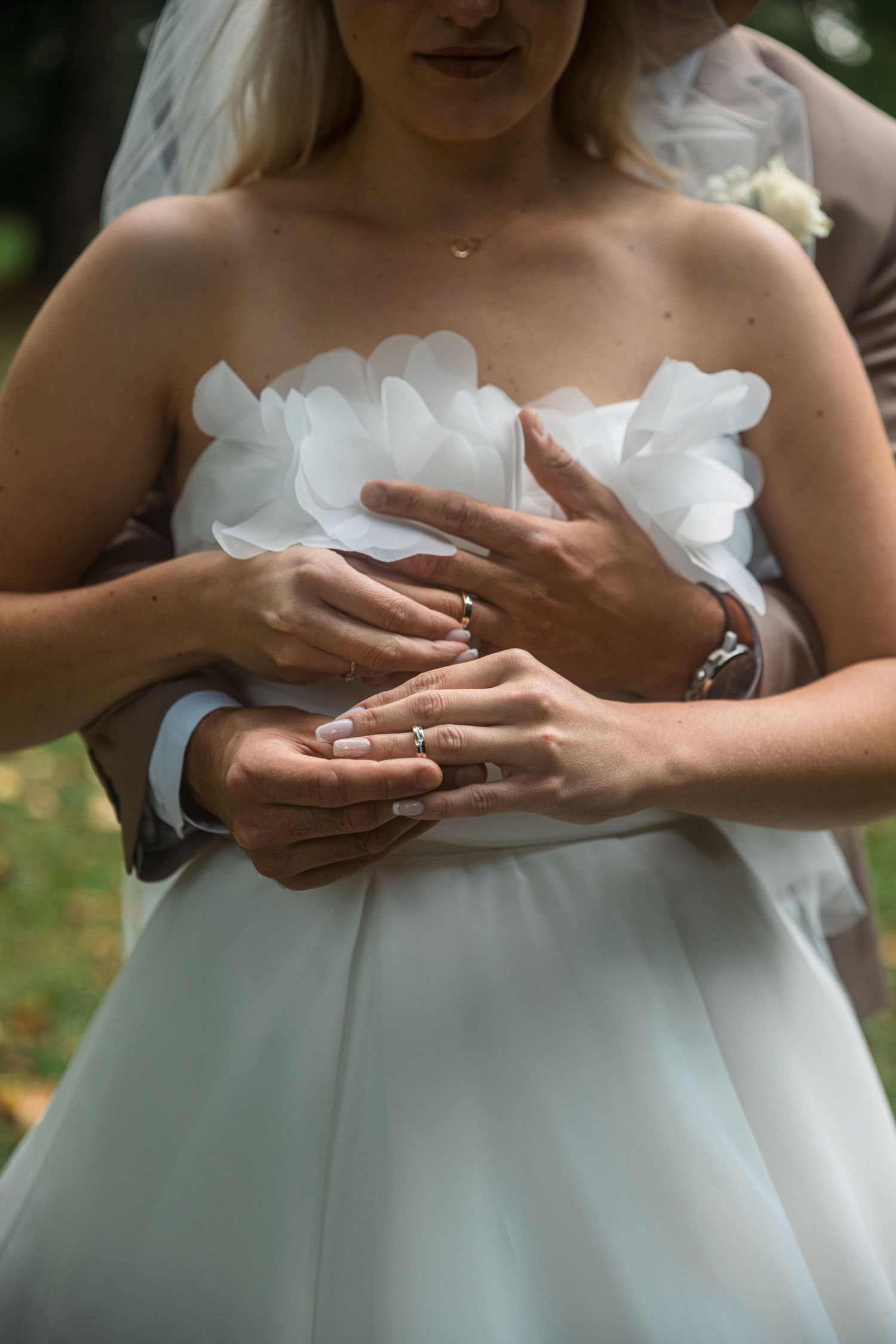 Close-up of hands adjusting a white wedding dress bodice with delicate details.