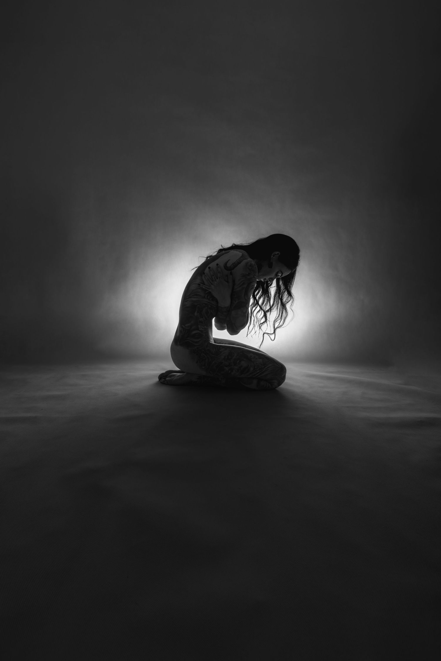 Dramatic black and white silhouette poses against a backlit studio setting.