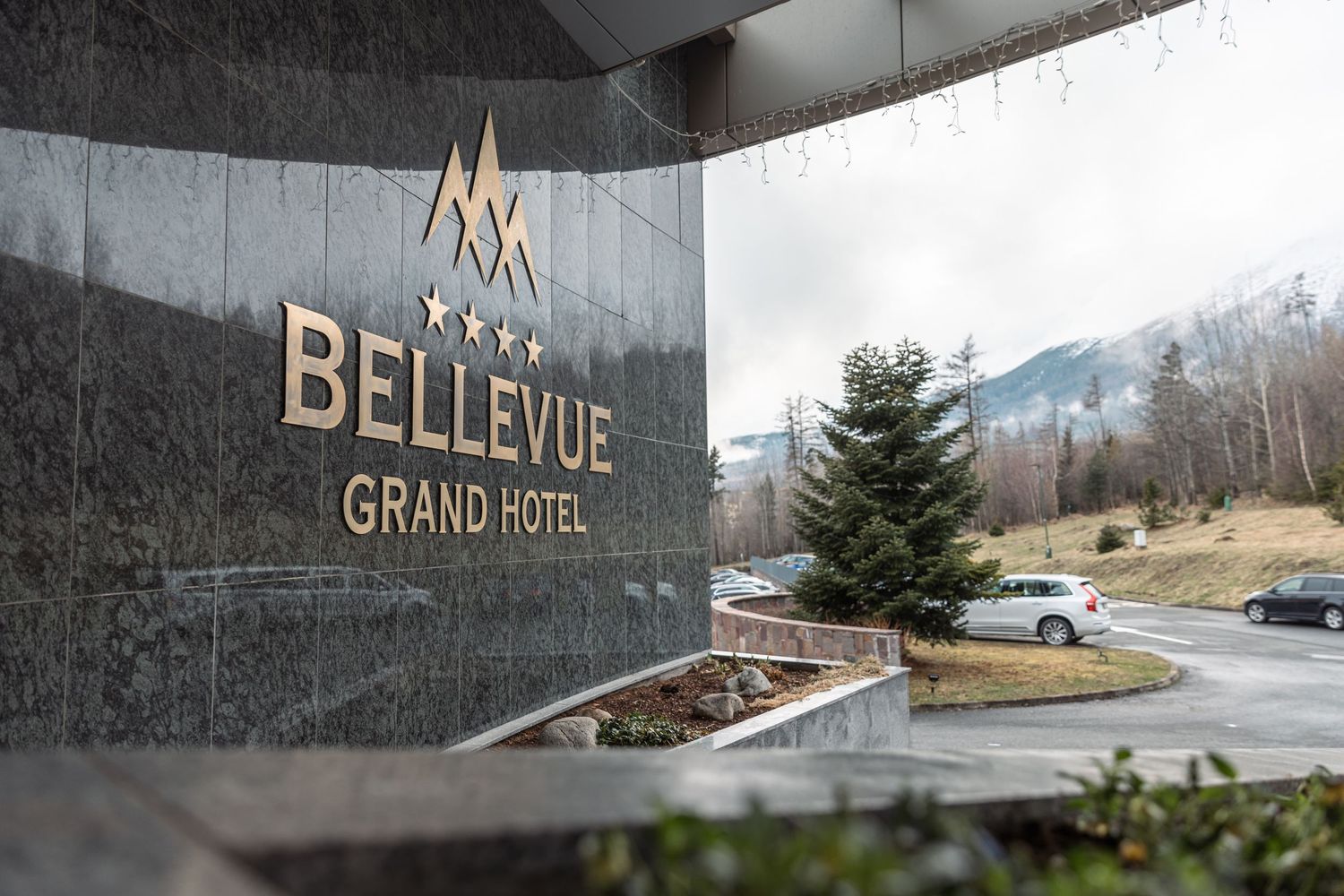 Exterior signage of Bellevue Grand Hotel with mountain landscape in background.