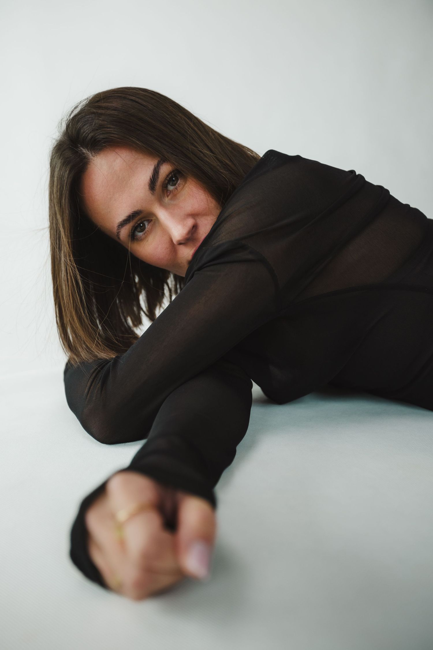 Woman in black long sleeve top lying on floor during artistic photoshoot.