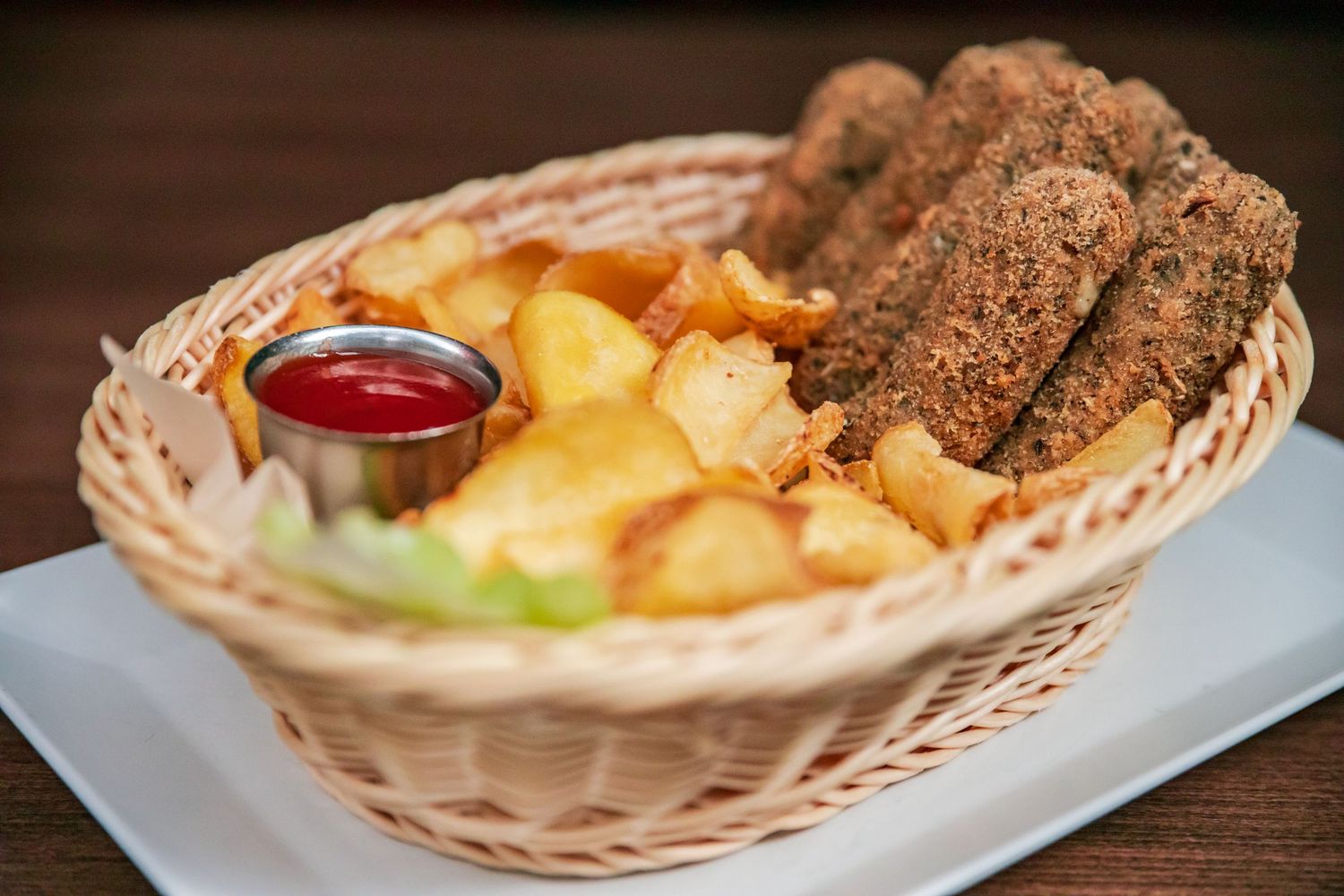 Bread basket and appetizer plates arranged on wooden restaurant table.