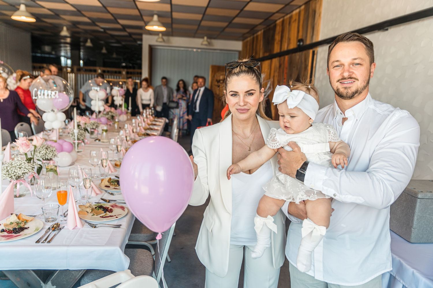 Wedding reception venue with elegant table settings and pink balloon decorations.