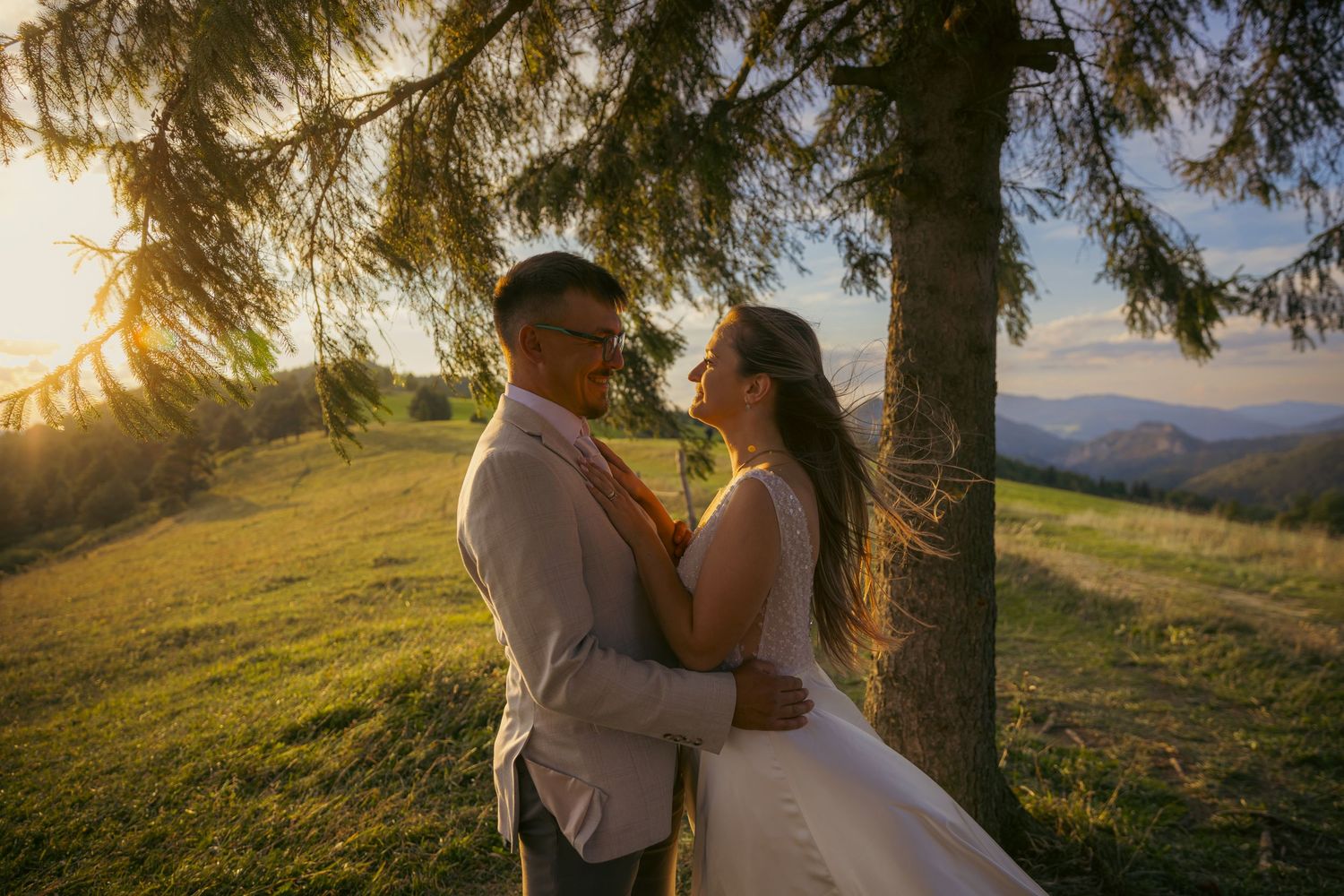 Romantic sunset wedding photos beneath towering evergreen trees in the mountains.