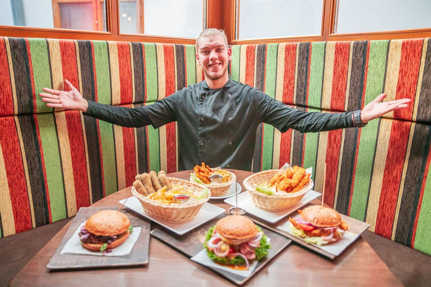 Restaurant booth with striped cushions displaying multiple plates of food.