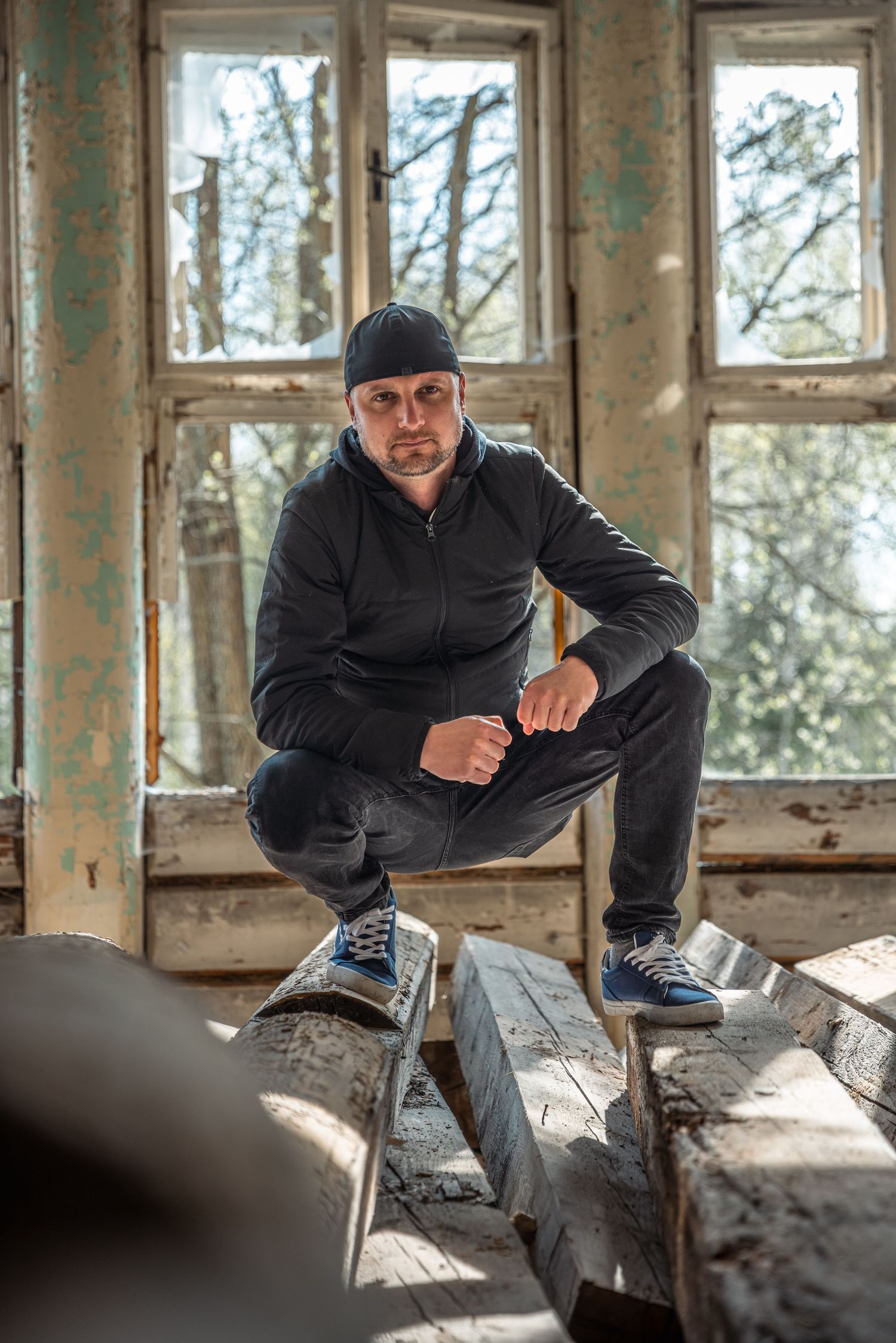 Urban explorer photographs inside a decaying building with broken windows.