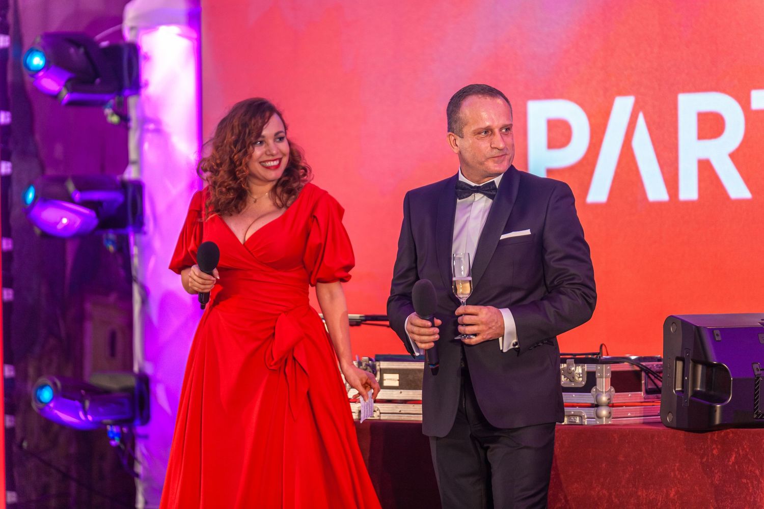 Formal gala event with dramatic red and purple stage lighting illuminating the dance floor.