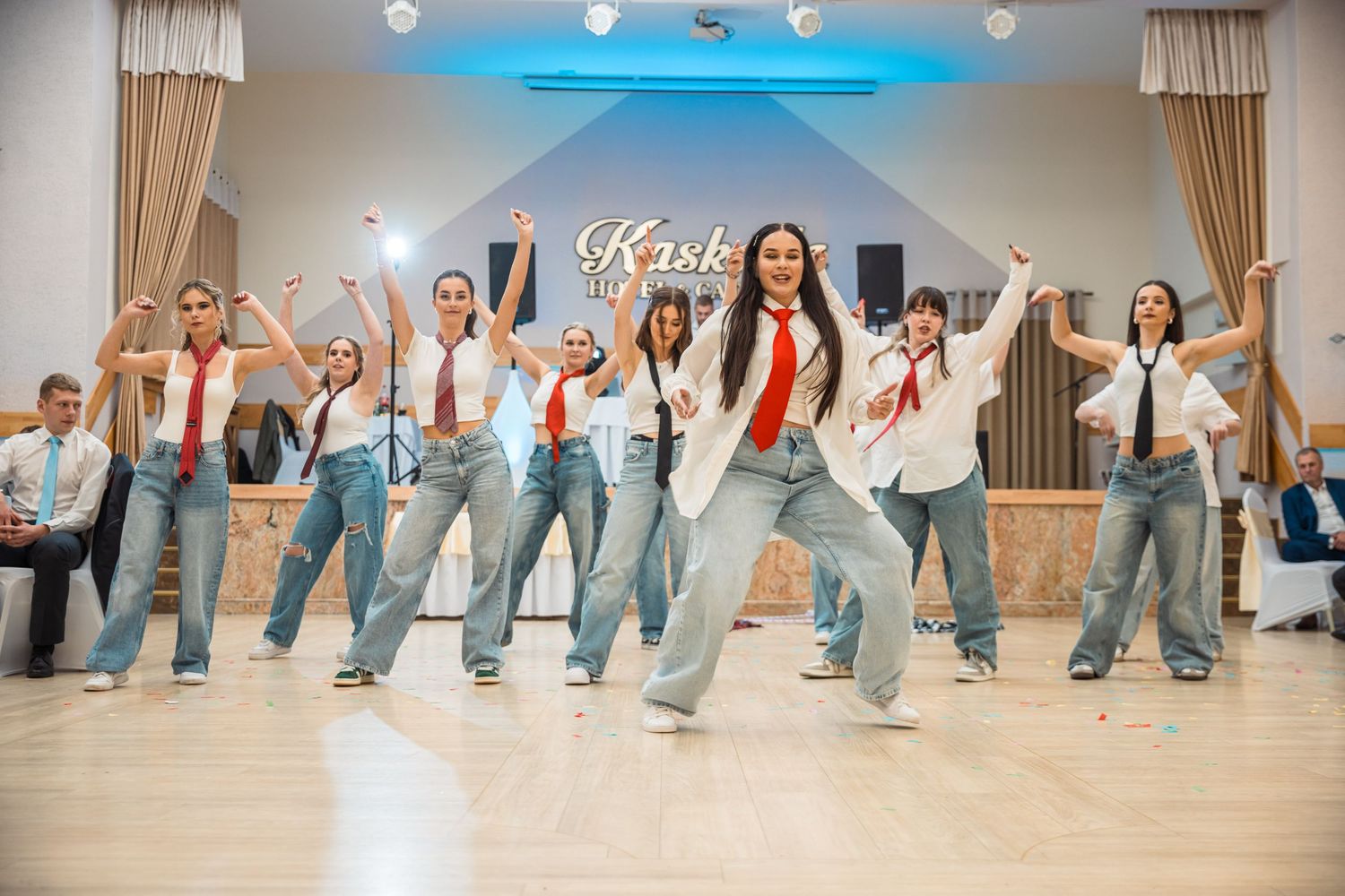 Group dance performance with participants in matching jeans creating synchronized line formation.