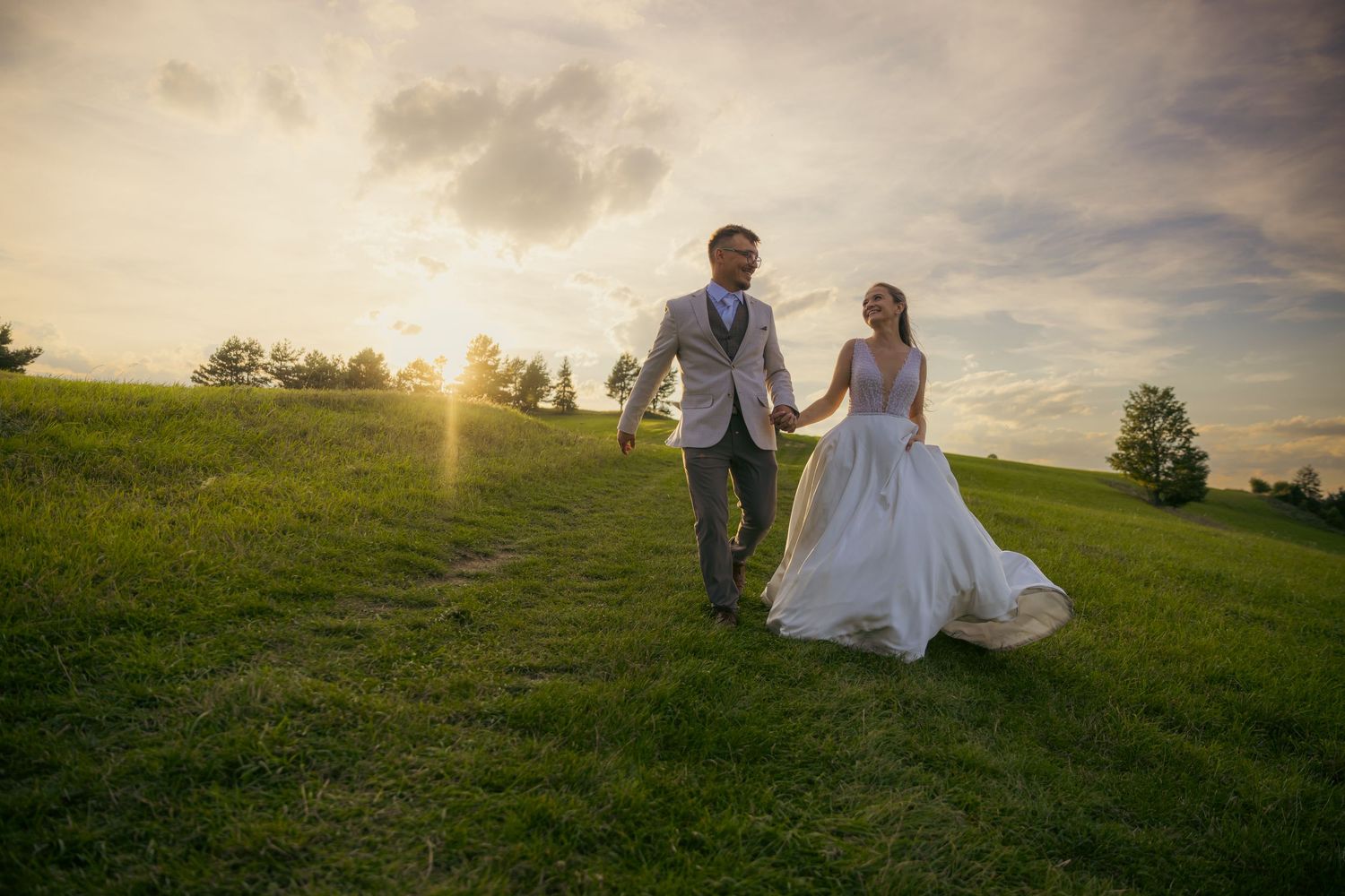 Romantic wedding couple silhouetted against a dramatic mountain sunset.