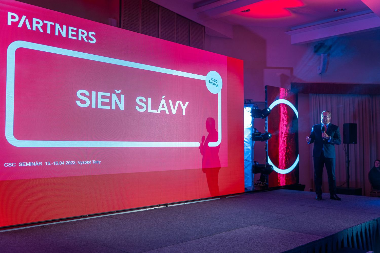 Corporate event stage with red illuminated Partners banner displaying 'SIEN SLAVY' text.