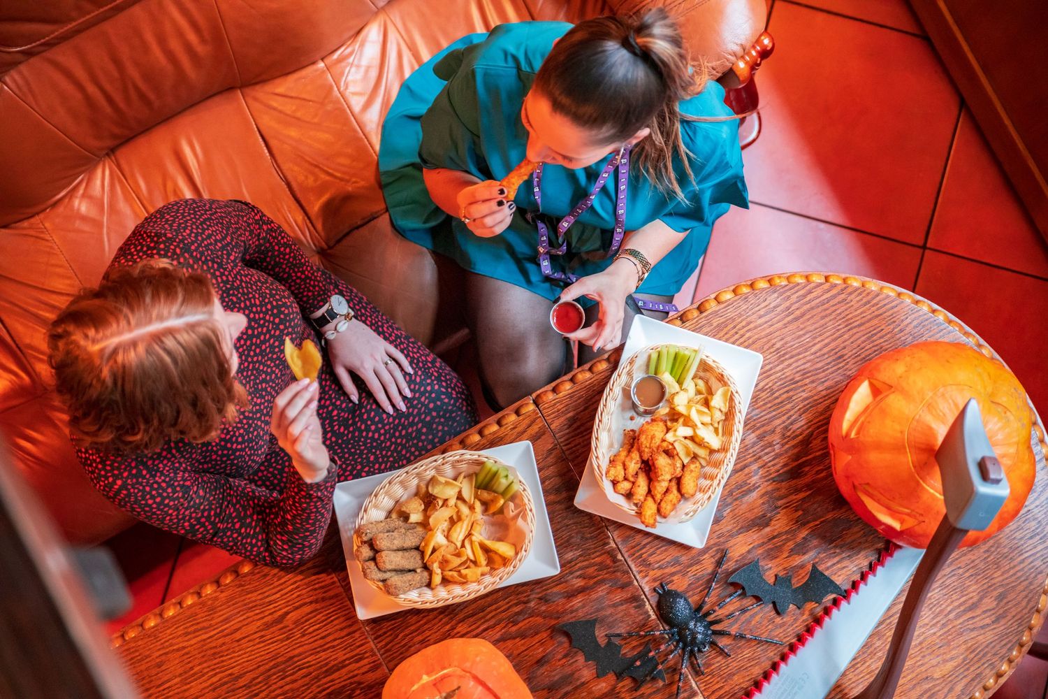 Overhead view of people enjoying snacks and refreshments on red table settings.