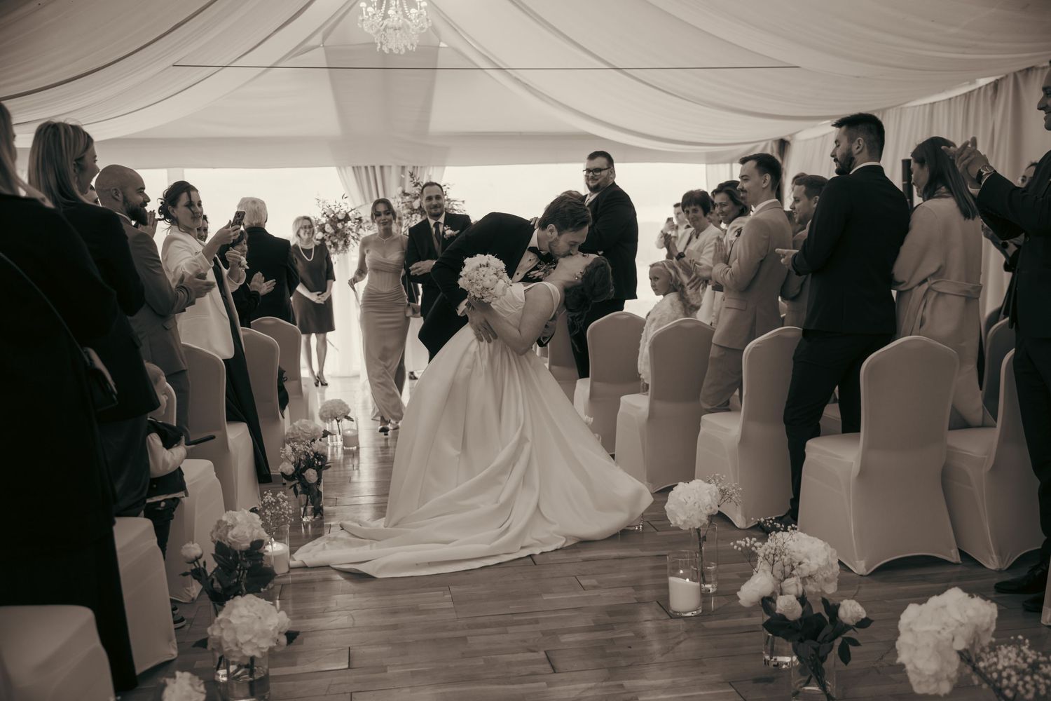 Black and white photo of wedding reception dancing under draped fabric ceiling.