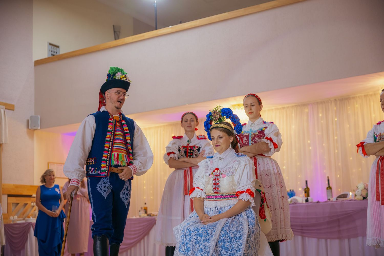 Wedding reception party with guests in traditional folk costumes and decorative banners.