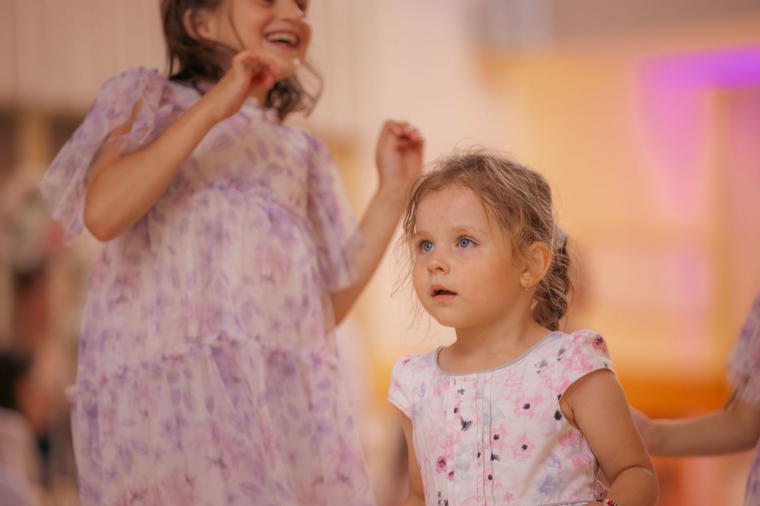 Young flower girl in a purple dress smiling during wedding festivities.